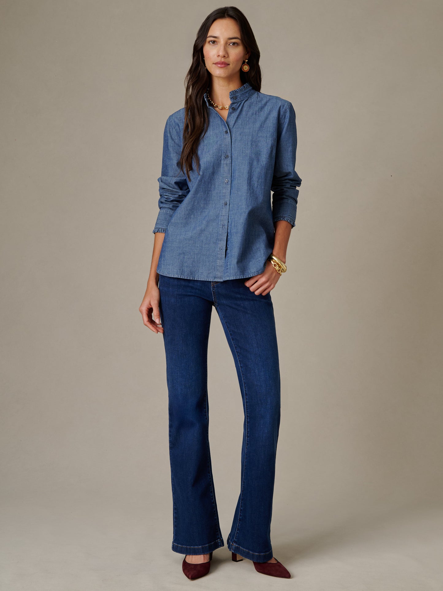 Woman models the Tess Ruffle Collar Chambray Shirt by J.McLaughlin, paired with dark jeans and stylish accessories in a timeless, effortlessly stylish look.