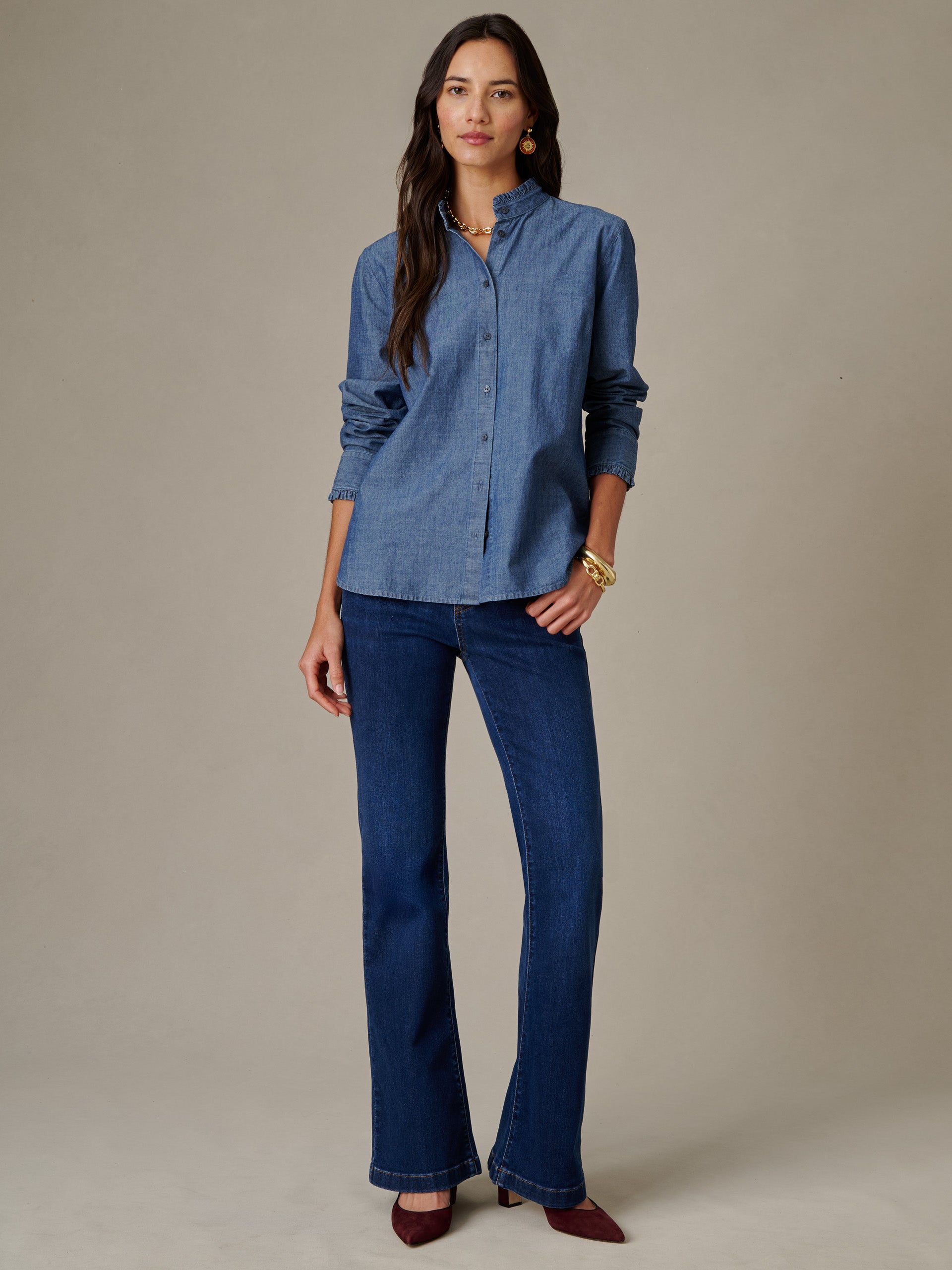 Woman models the Tess Ruffle Collar Chambray Shirt by J.McLaughlin, paired with dark jeans and stylish accessories in a timeless, effortlessly stylish look.