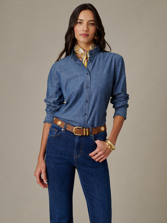 Woman wearing a Tess Ruffle Collar Chambray Shirt from J.McLaughlin paired with dark jeans, a brown belt, gold jewelry, and a patterned silk scarf, showcasing timeless style.