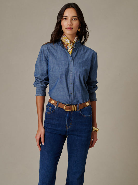 Woman wearing a Tess Ruffle Collar Chambray Shirt from J.McLaughlin paired with dark jeans, a brown belt, gold jewelry, and a patterned silk scarf, showcasing timeless style.