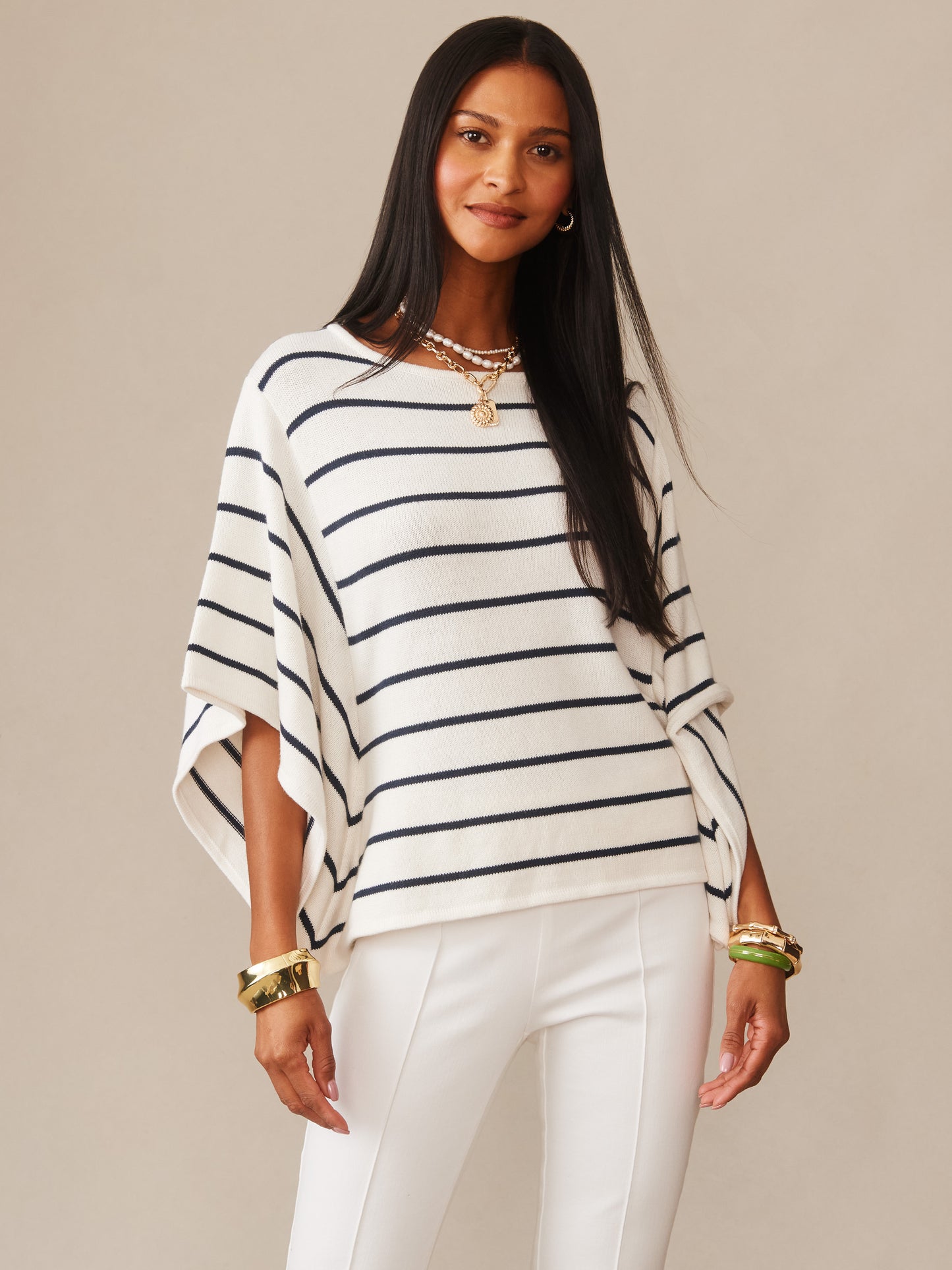 Woman wearing Thea Sweater in Stripe by J.McLaughlin, featuring navy stripes on a white background, styled with white pants and gold accessories, showcasing effortlessly stylish, enduring designs with innovative fabrics, a destination for defining style. Life, Well-Lived.