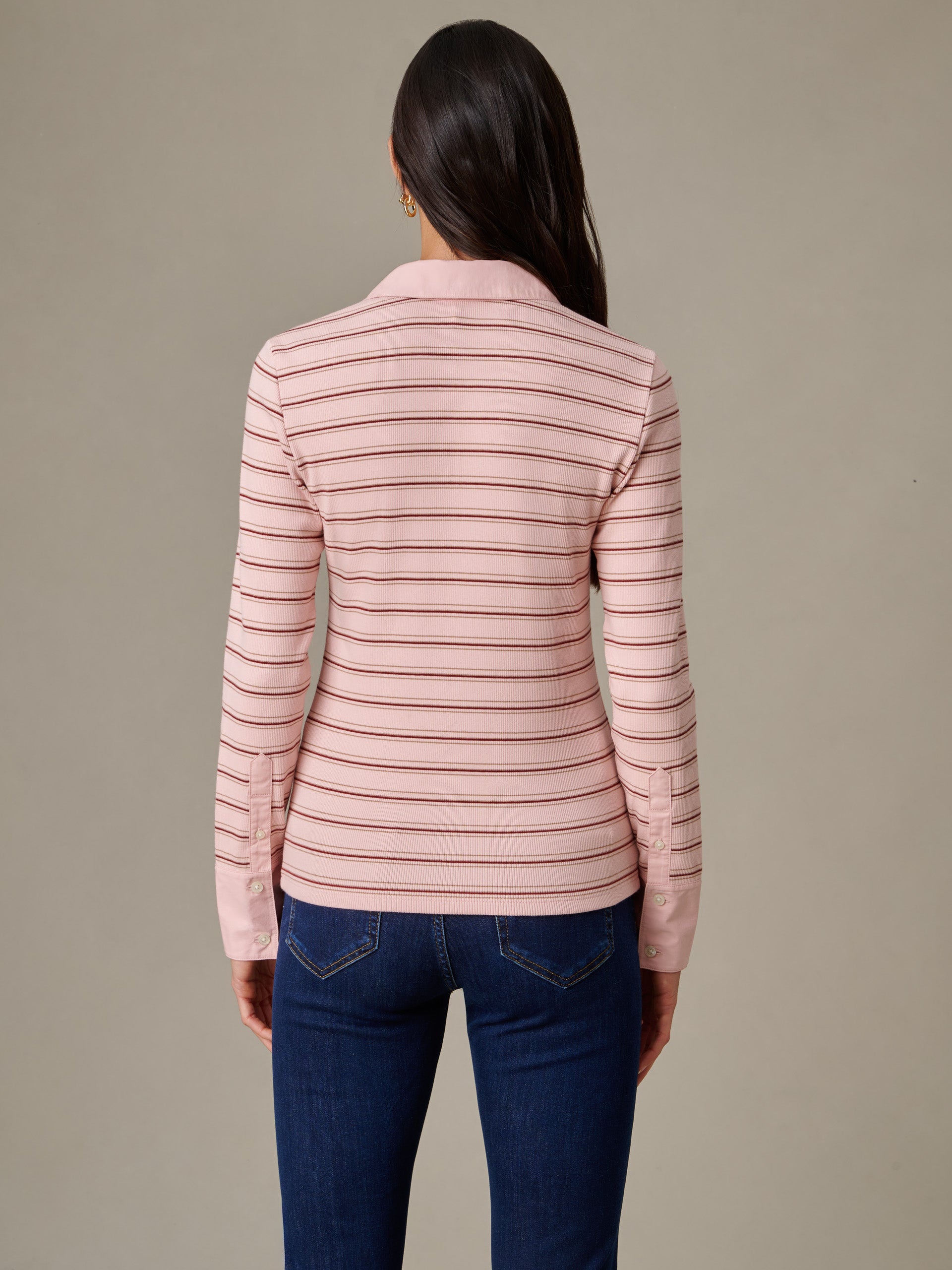 Woman facing away wearing Theodora Shirt in Stripe by J.McLaughlin, featuring soft pink and thin horizontal stripes and classic tailored cuffs, paired with dark jeans.