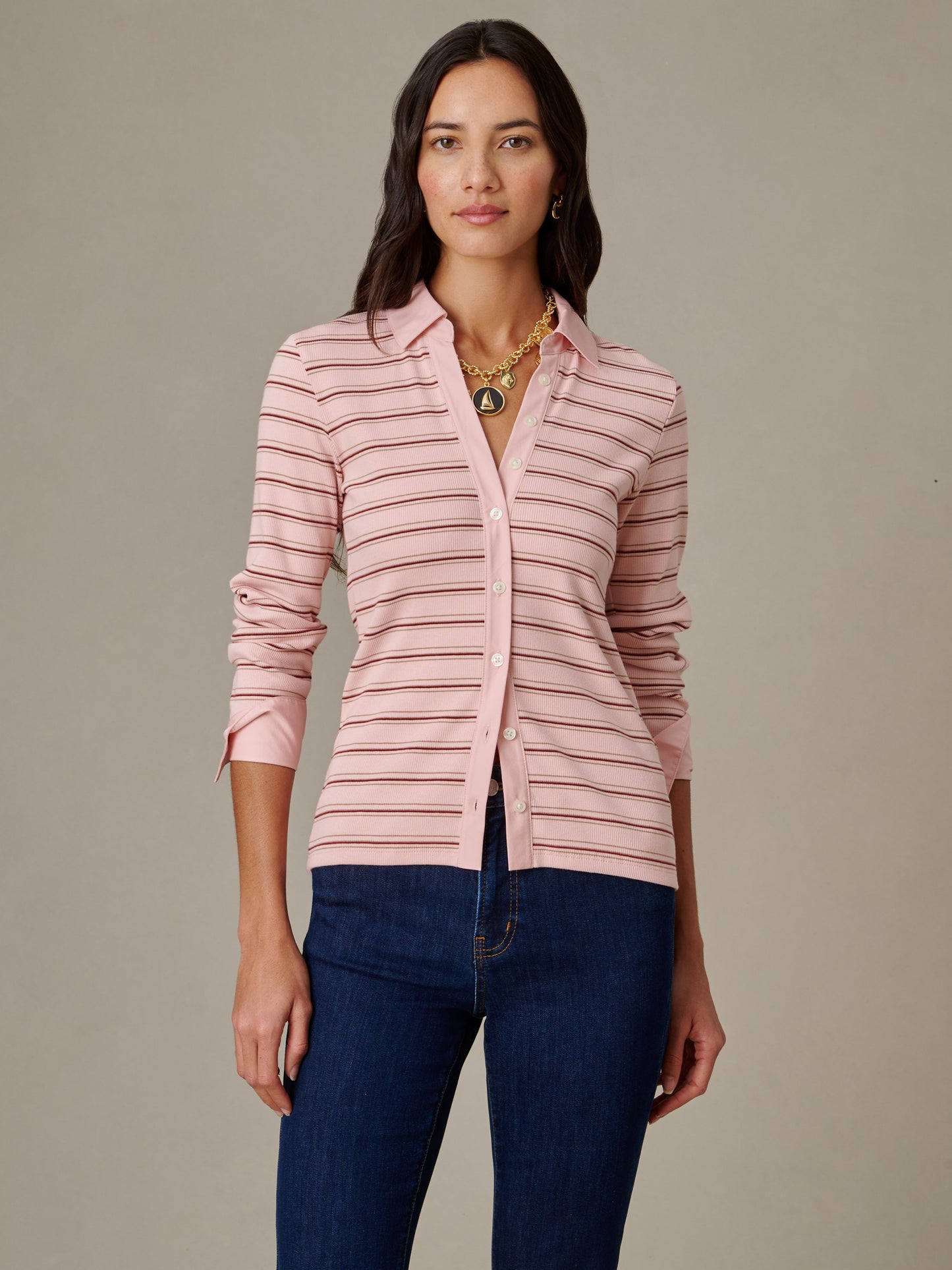 Woman wearing Theodora Shirt in Stripe by J.McLaughlin, featuring soft pink and brown horizontal stripes with a classic collar and button-down front, paired with dark blue jeans.