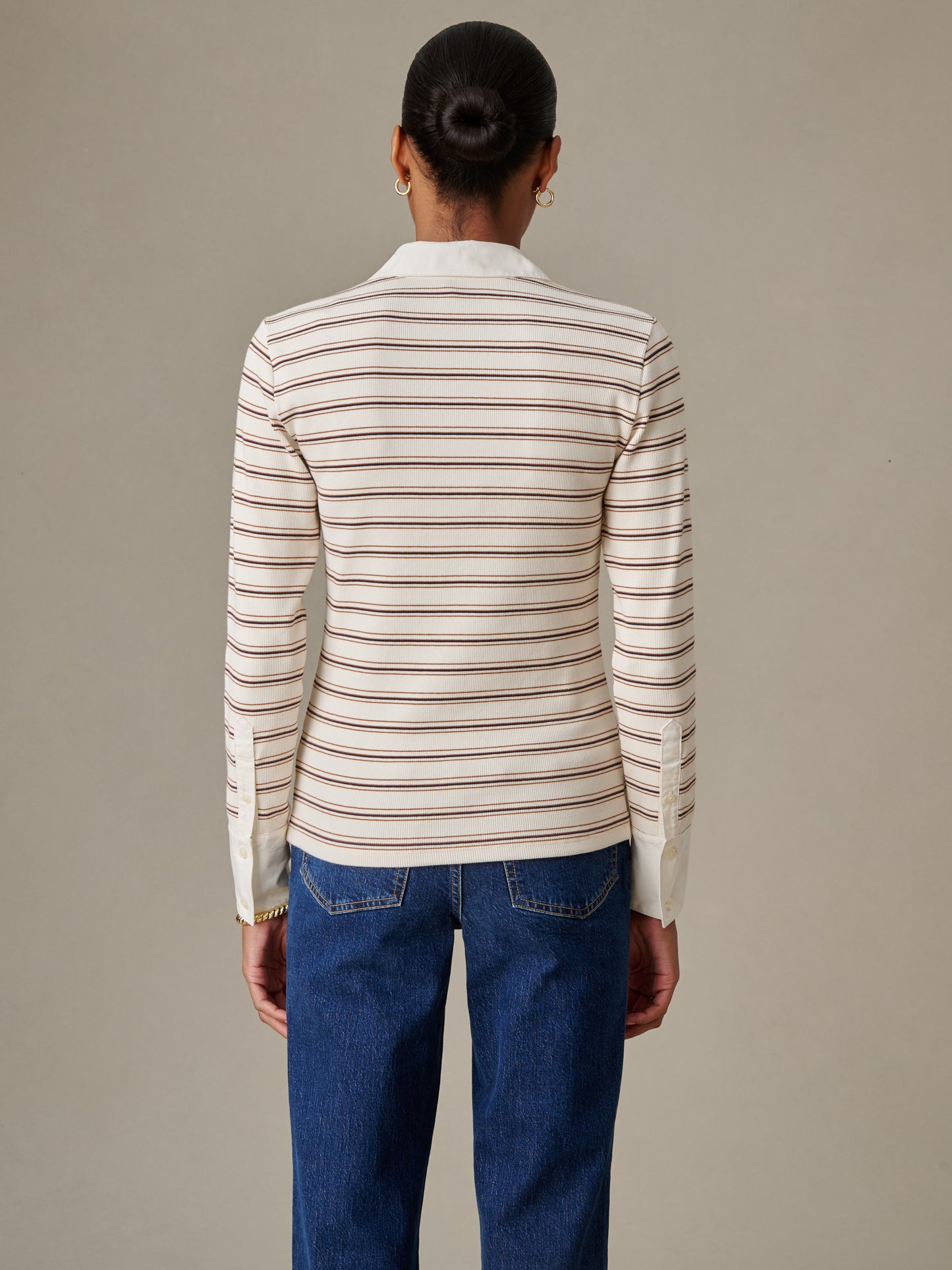 Back view of a woman wearing Theodora Shirt in Stripe by J.McLaughlin, featuring an effortlessly stylish striped blouse paired with classic blue jeans, showcasing enduring design and craftsmanship.