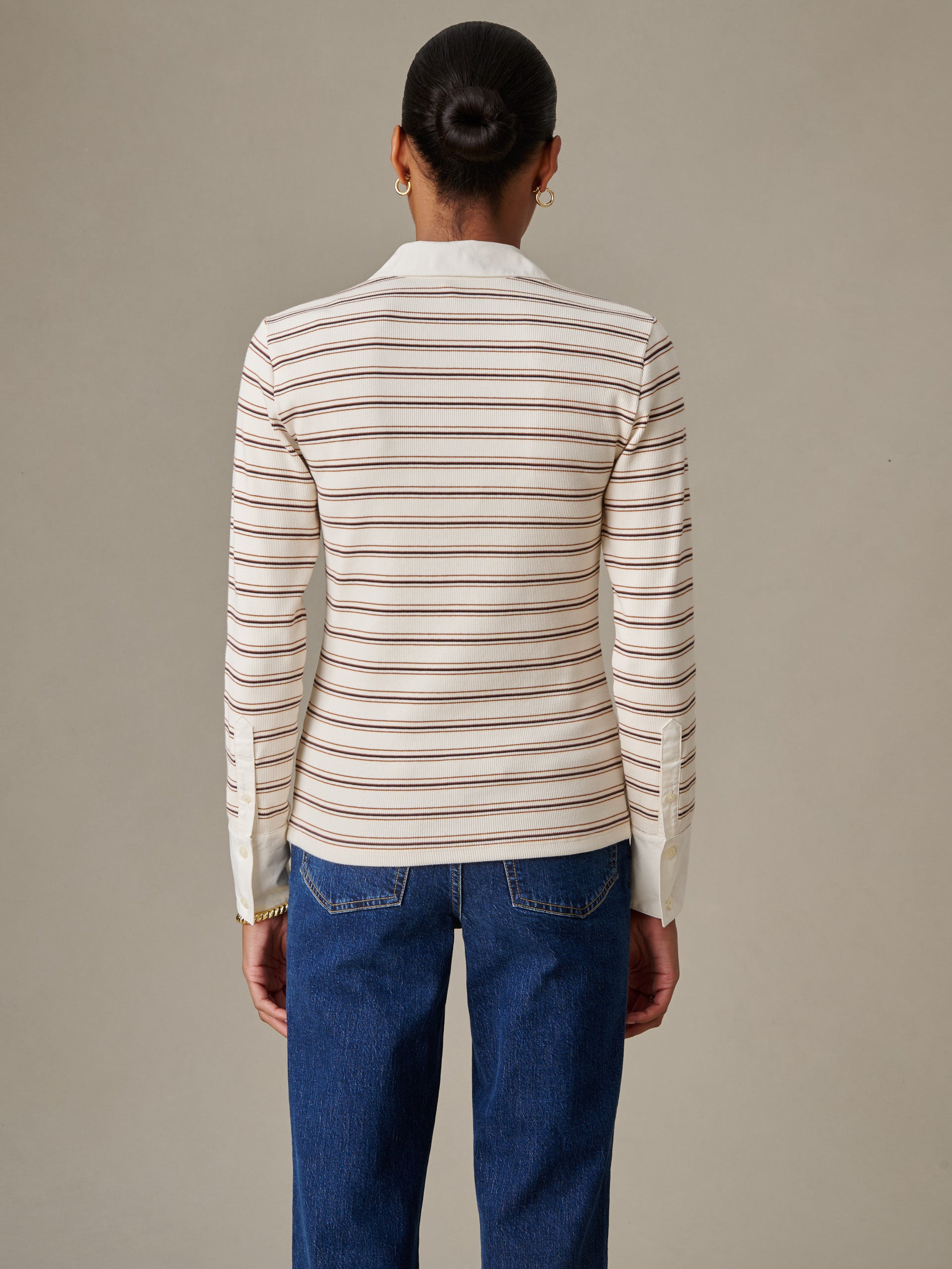 Back view of a woman wearing Theodora Shirt in Stripe by J.McLaughlin, featuring an effortlessly stylish striped blouse paired with classic blue jeans, showcasing enduring design and craftsmanship.