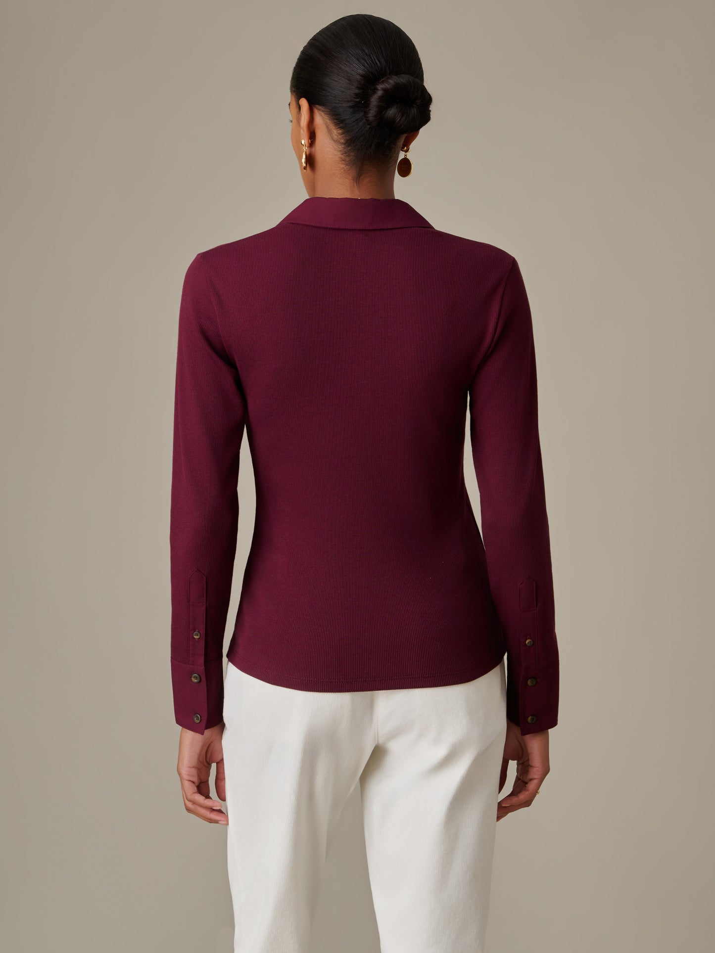 Woman seen from behind wearing J.McLaughlin Theodora Shirt in deep burgundy paired with white pants, showcasing timeless style and impeccable craftsmanship.