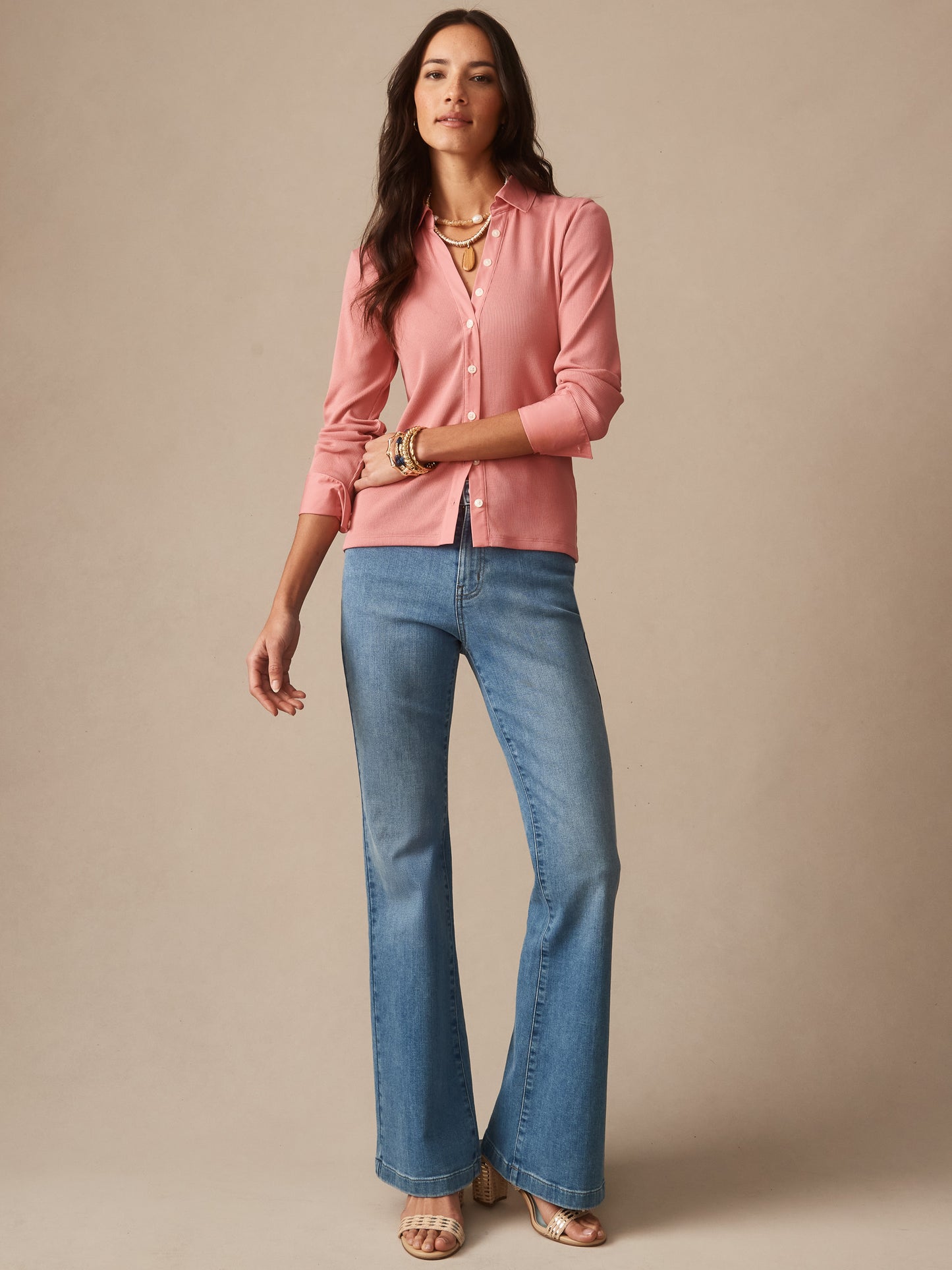 Woman wearing a mauve Theodora Shirt by J.McLaughlin paired with light blue jeans and layered necklaces, showcasing effortlessly stylish, enduring designs and innovative fabrics.
