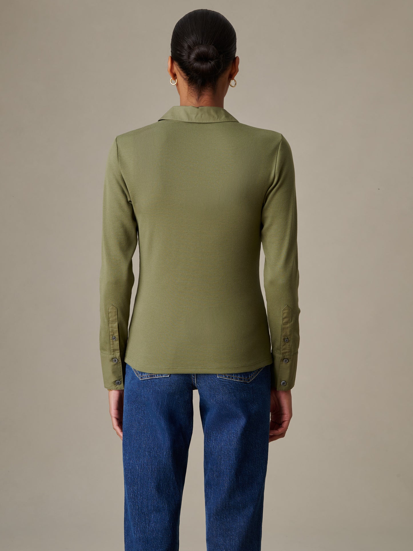 Woman wearing an olive green Theodora Shirt by J.McLaughlin paired with classic blue jeans, showcasing effortlessly stylish and enduring design for a life well-lived.