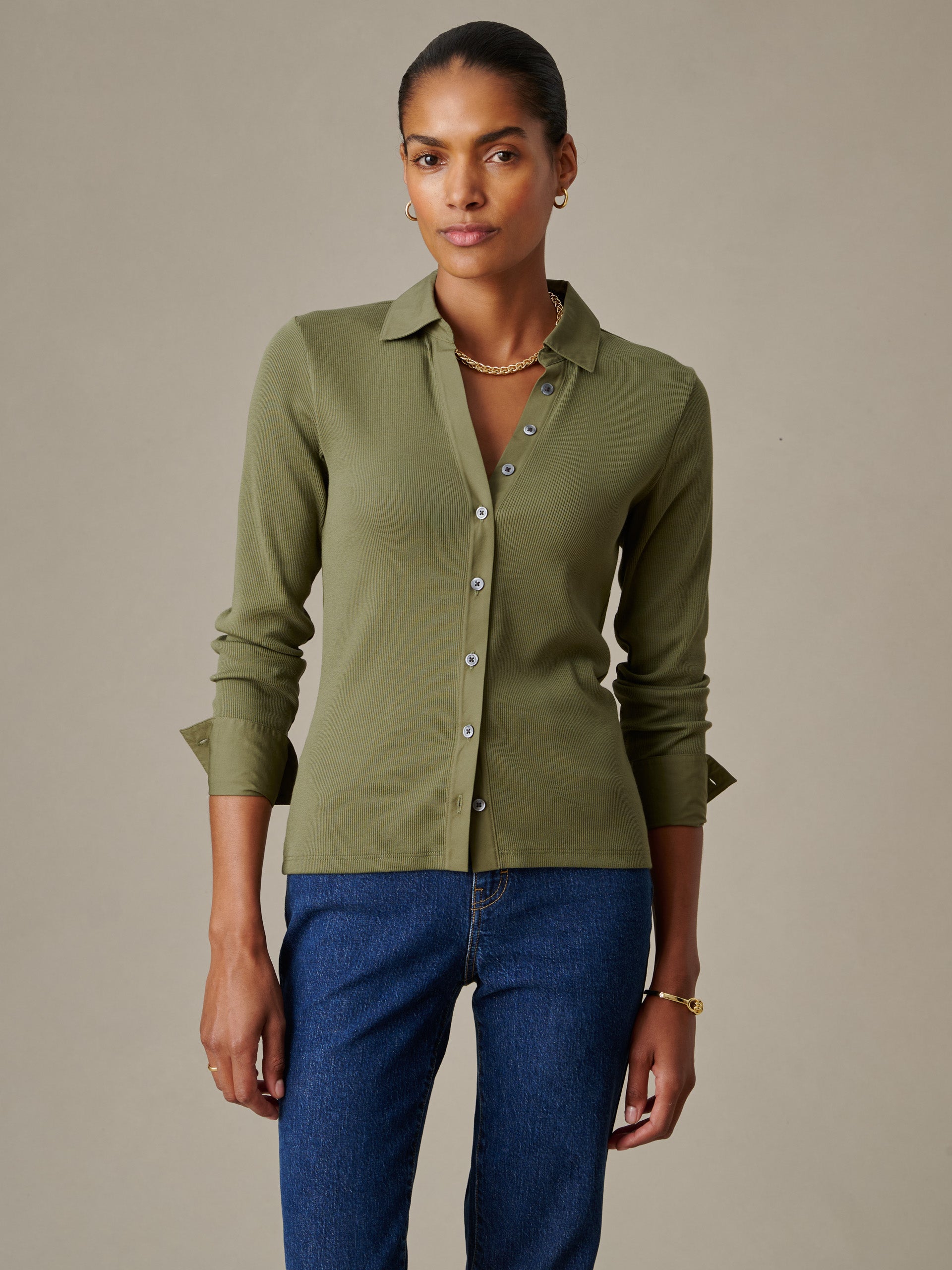 Woman wearing Theodora Shirt in olive green by J.McLaughlin, paired with blue jeans, showcasing effortlessly stylish and enduring designs with classic appeal.