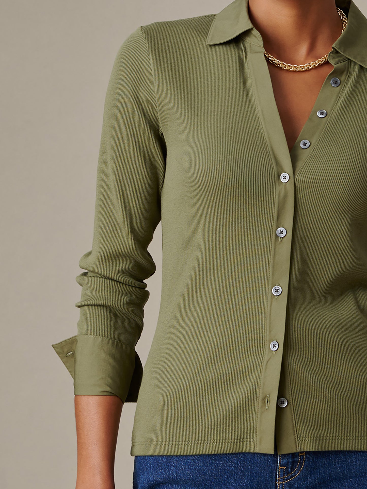 Close-up of a person wearing the olive green Theodora Shirt by J.McLaughlin, featuring a ribbed texture, button-down front, and a gold chain necklace, showcasing effortless style.