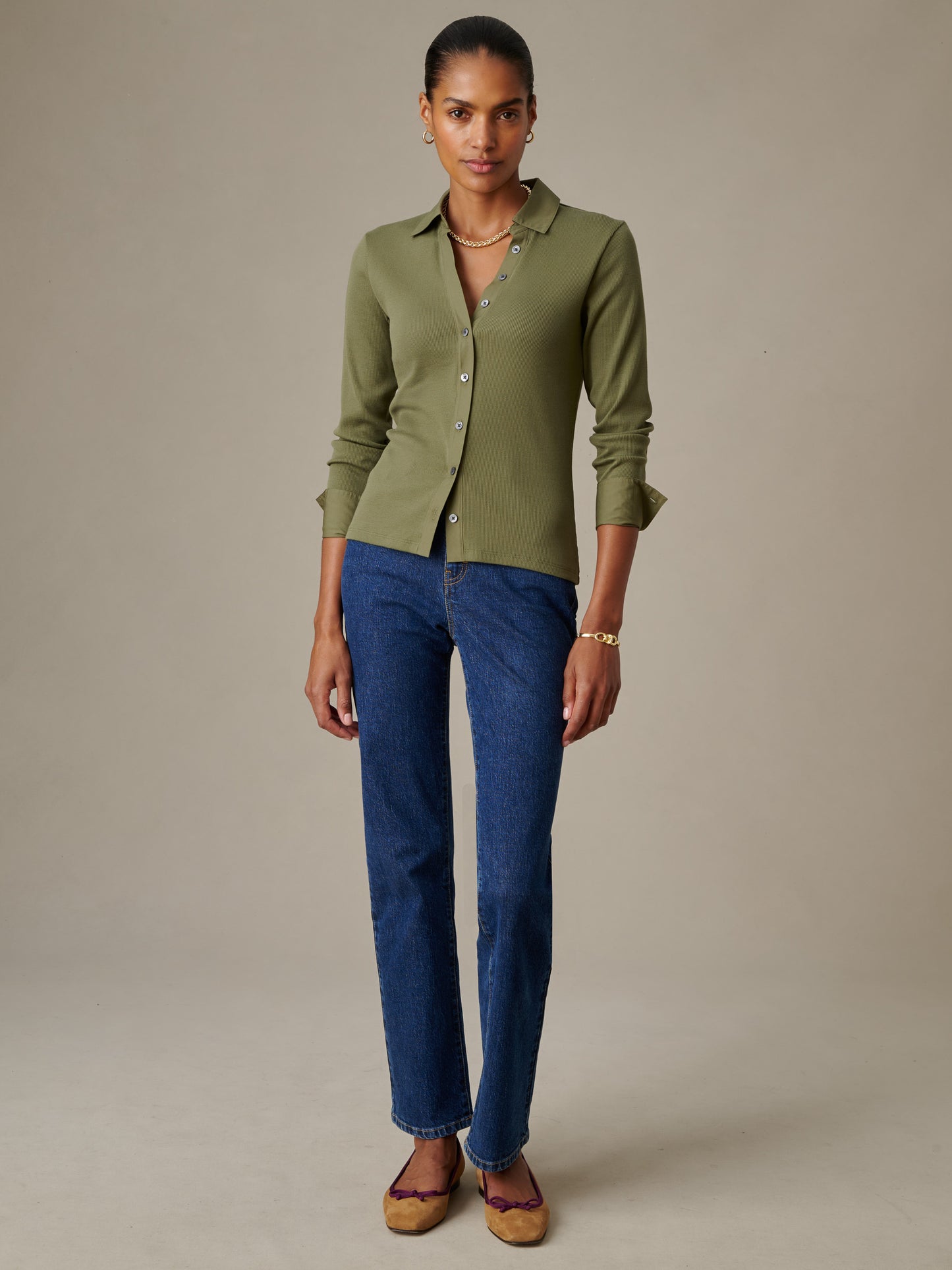 Woman wearing an olive green Theodora Shirt by J.McLaughlin paired with blue jeans, showcasing an effortlessly stylish and timeless look perfect for defining style.