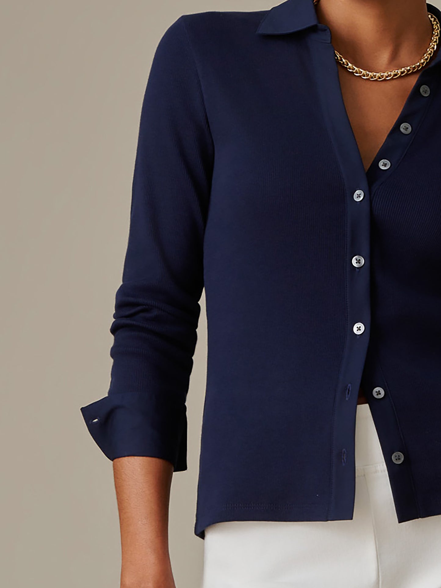 Close-up of a person wearing a navy blue Theodora Shirt from J.McLaughlin paired with white bottoms and a gold chain necklace, showcasing timeless style and craftsmanship.