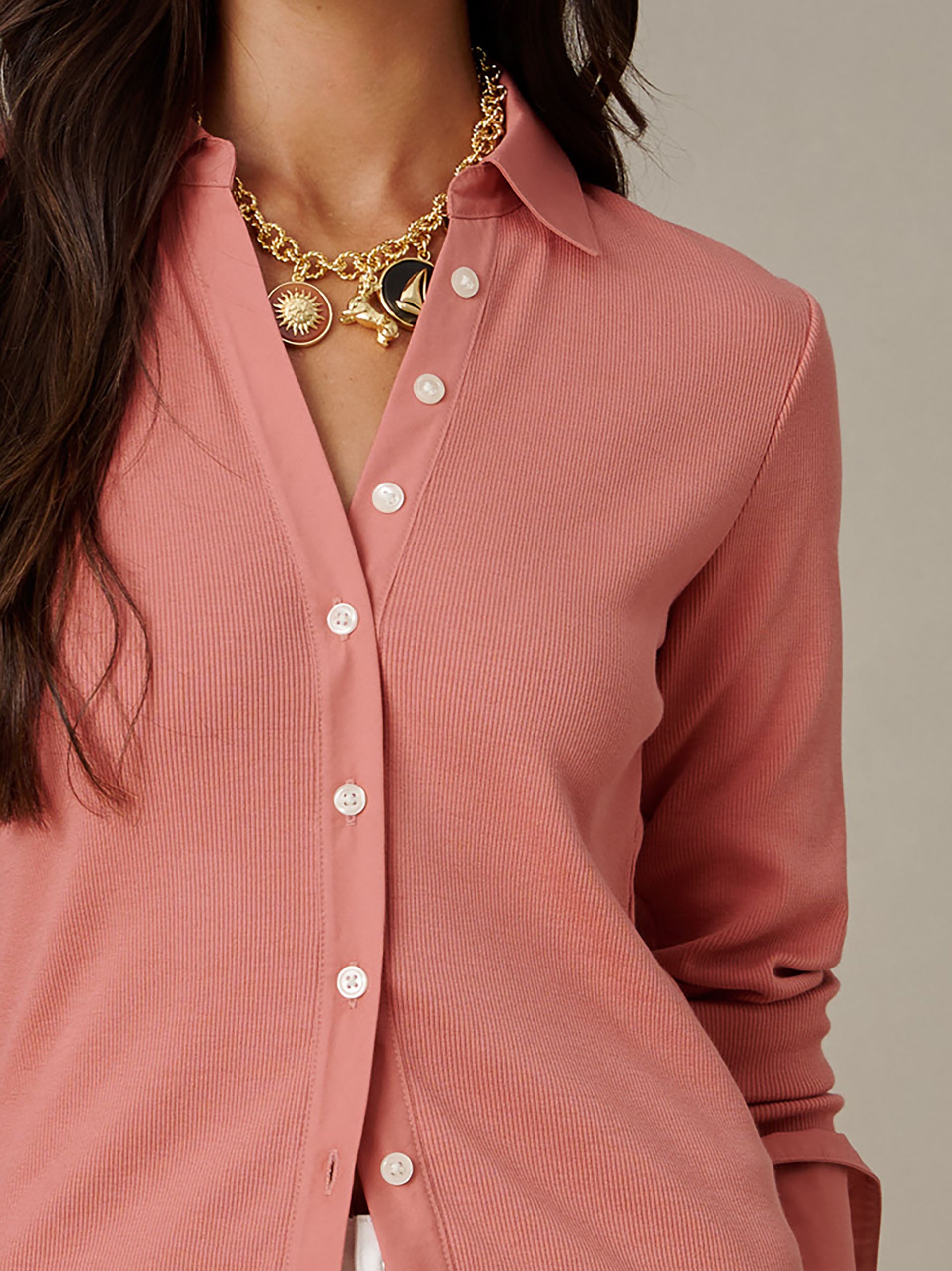Close-up of a woman wearing Theodora Shirt by J.McLaughlin in a soft pink fabric paired with a gold chain necklace, showcasing effortlessly stylish and enduring design.