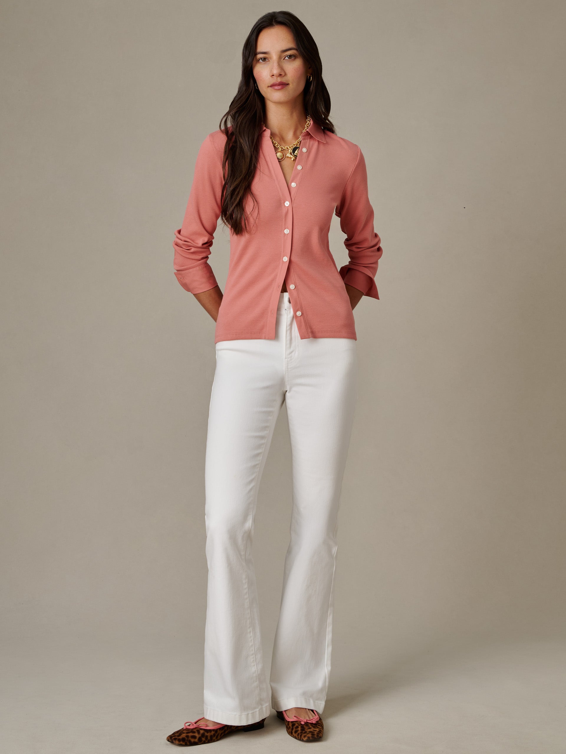 Woman wearing Theodora Shirt by J.McLaughlin in a soft rose color paired with white pants, styled simply to highlight the shirt’s effortlessly stylish, classic design.