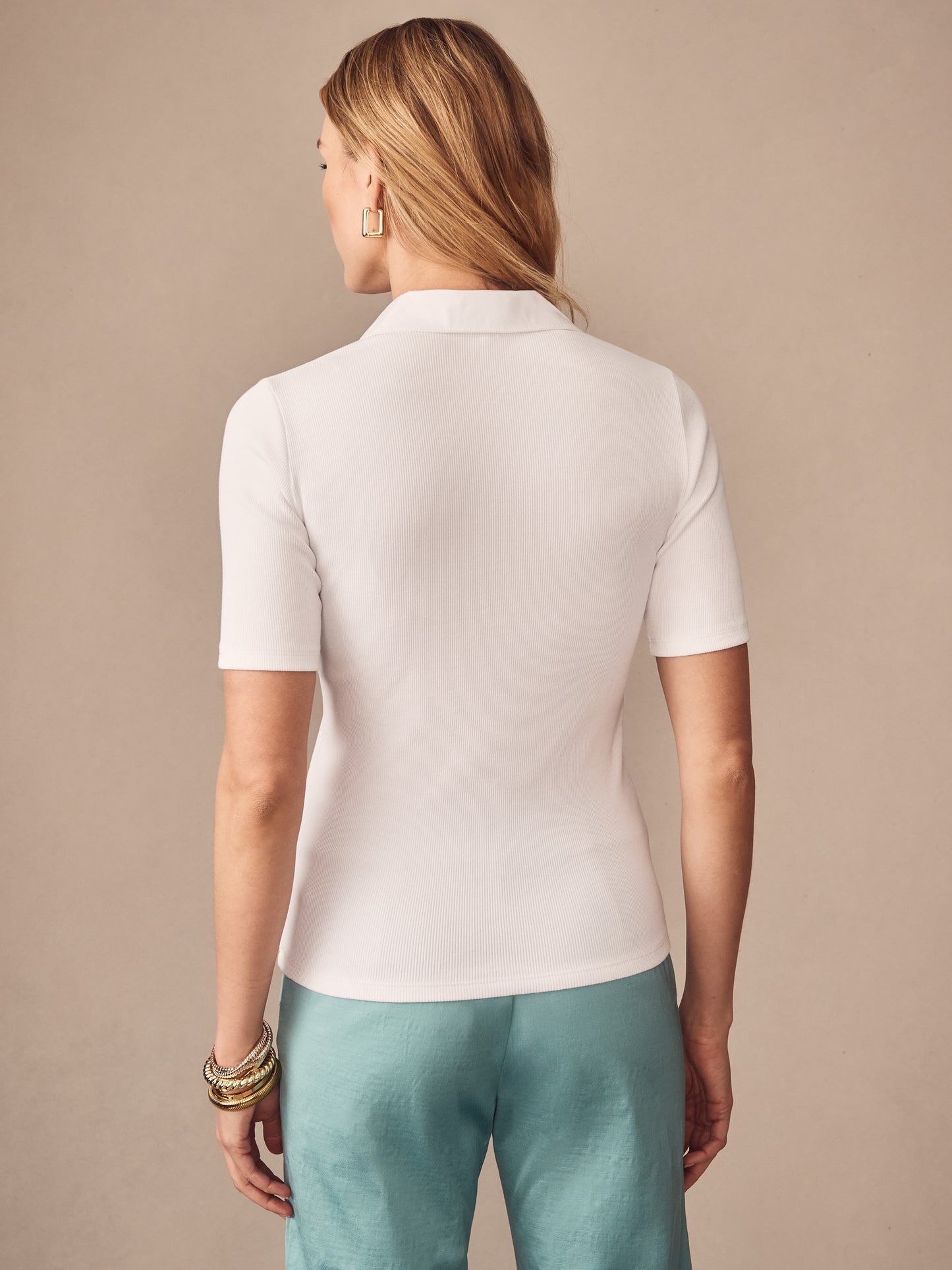 Woman wearing a white Theodora Short Sleeve Shirt by J.McLaughlin paired with light blue pants, showcasing effortlessly stylish and enduring designs in innovative fabrics, a destination for defining style. Life, Well-Lived.