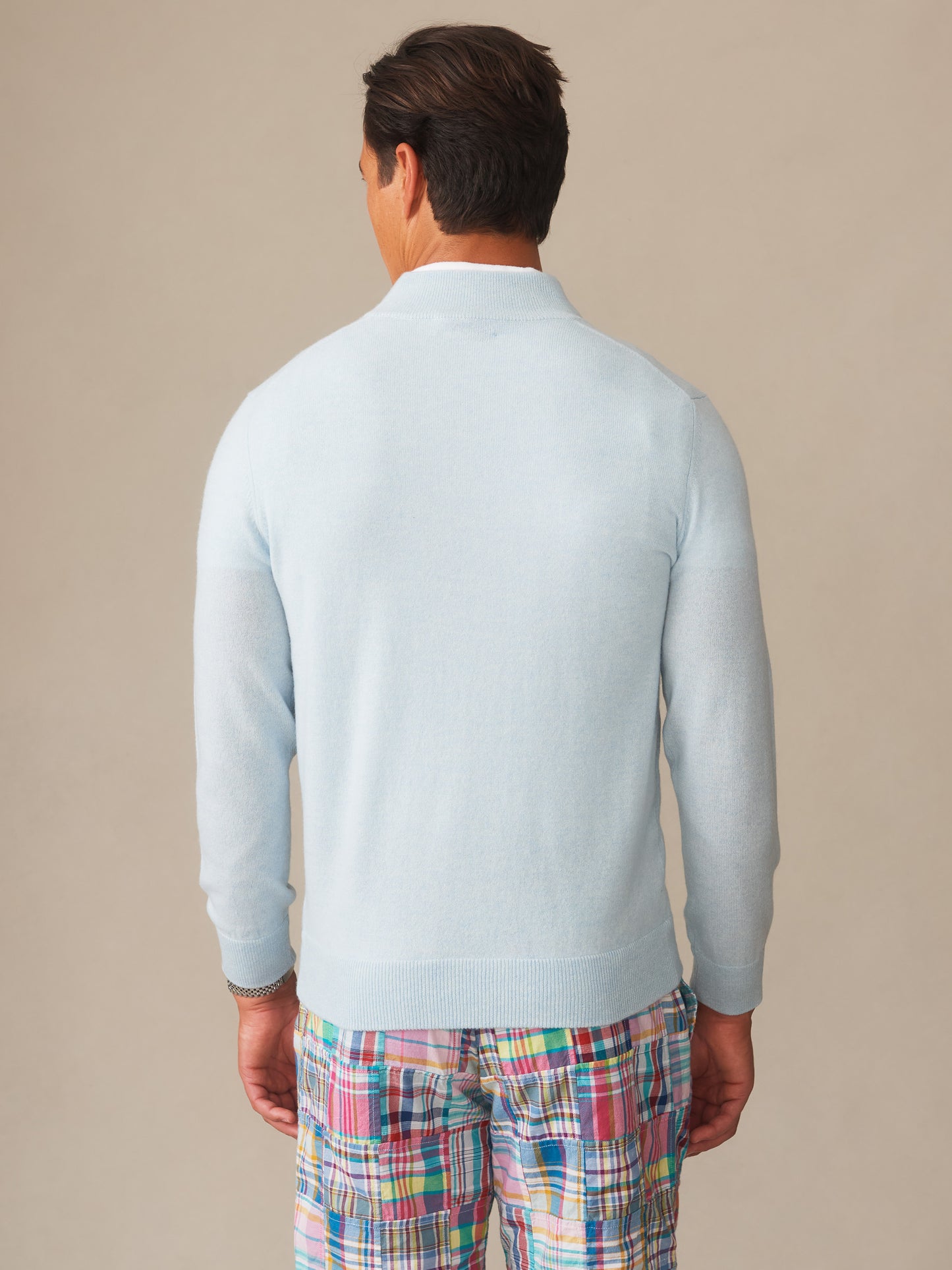 Man wearing a light blue Twain Cashmere 1/4 Zip sweater by J.McLaughlin paired with colorful plaid shorts, showcasing effortlessly stylish, enduring designs and an innovative fabric blend.