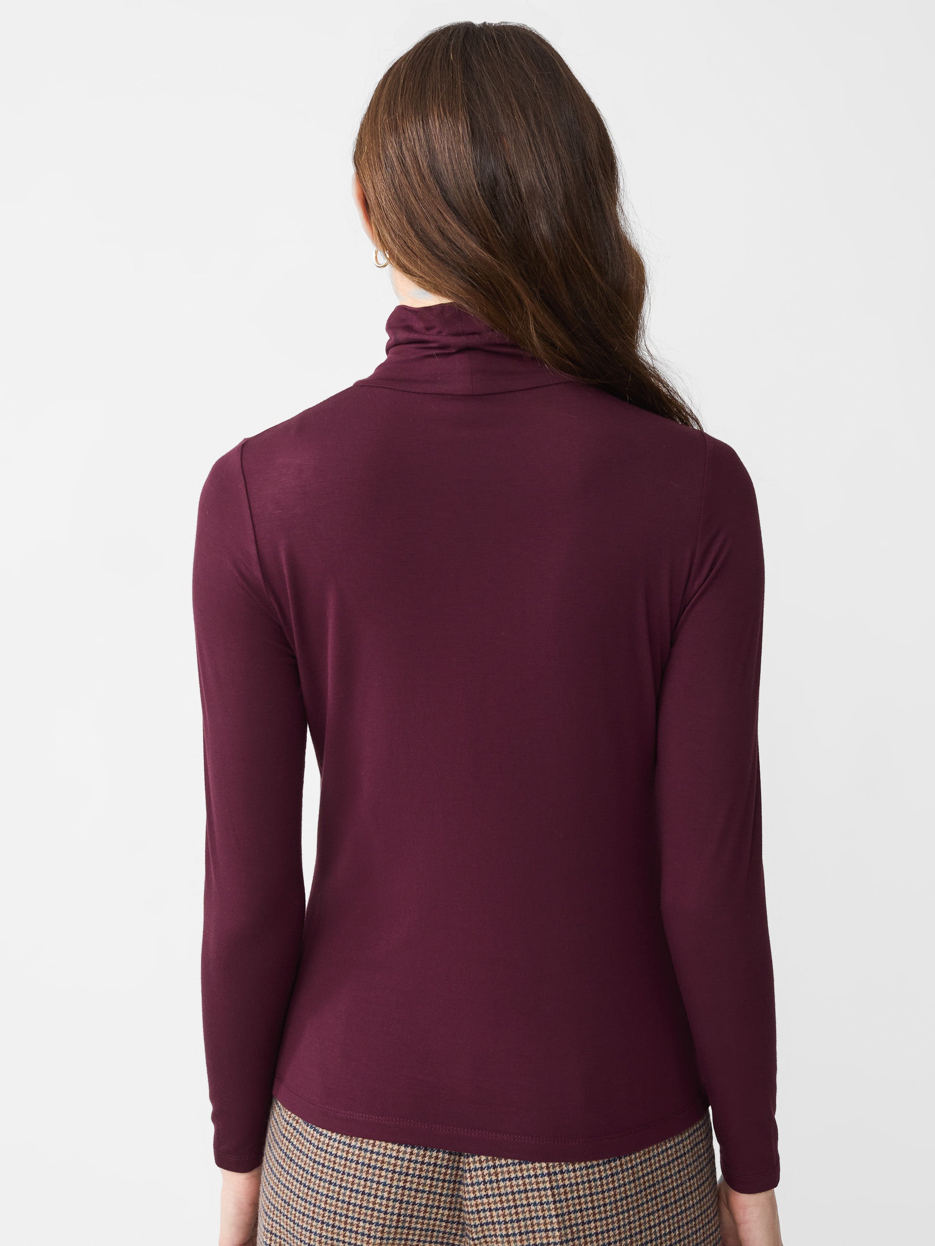 Model wearing J.McLaughlin Nadia turtleneck in burgundy made with rayon/spandex.