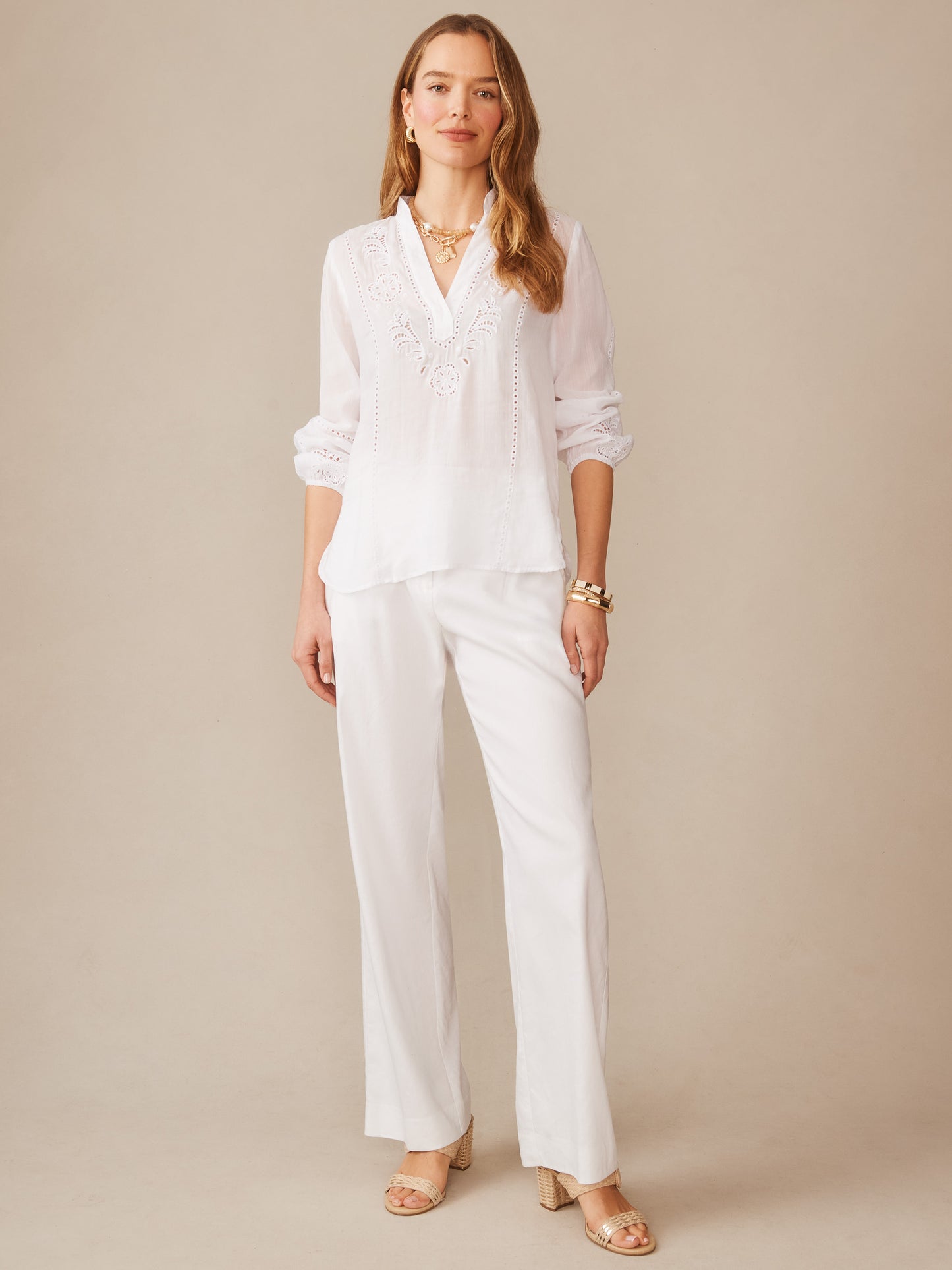 Woman wearing the Varsha Blouse by J.McLaughlin, featuring intricate detailing in a crisp white fabric paired with wide-leg trousers, embodying effortlessly stylish, enduring designs with a legacy of timeless fashion. A destination for defining style. Life, Well-Lived.