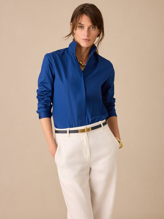 Woman wearing a navy blue Victoria Shirt by J.McLaughlin paired with white pants and a black belt, showcasing effortlessly stylish, enduring designs and a legacy of timeless fashion.