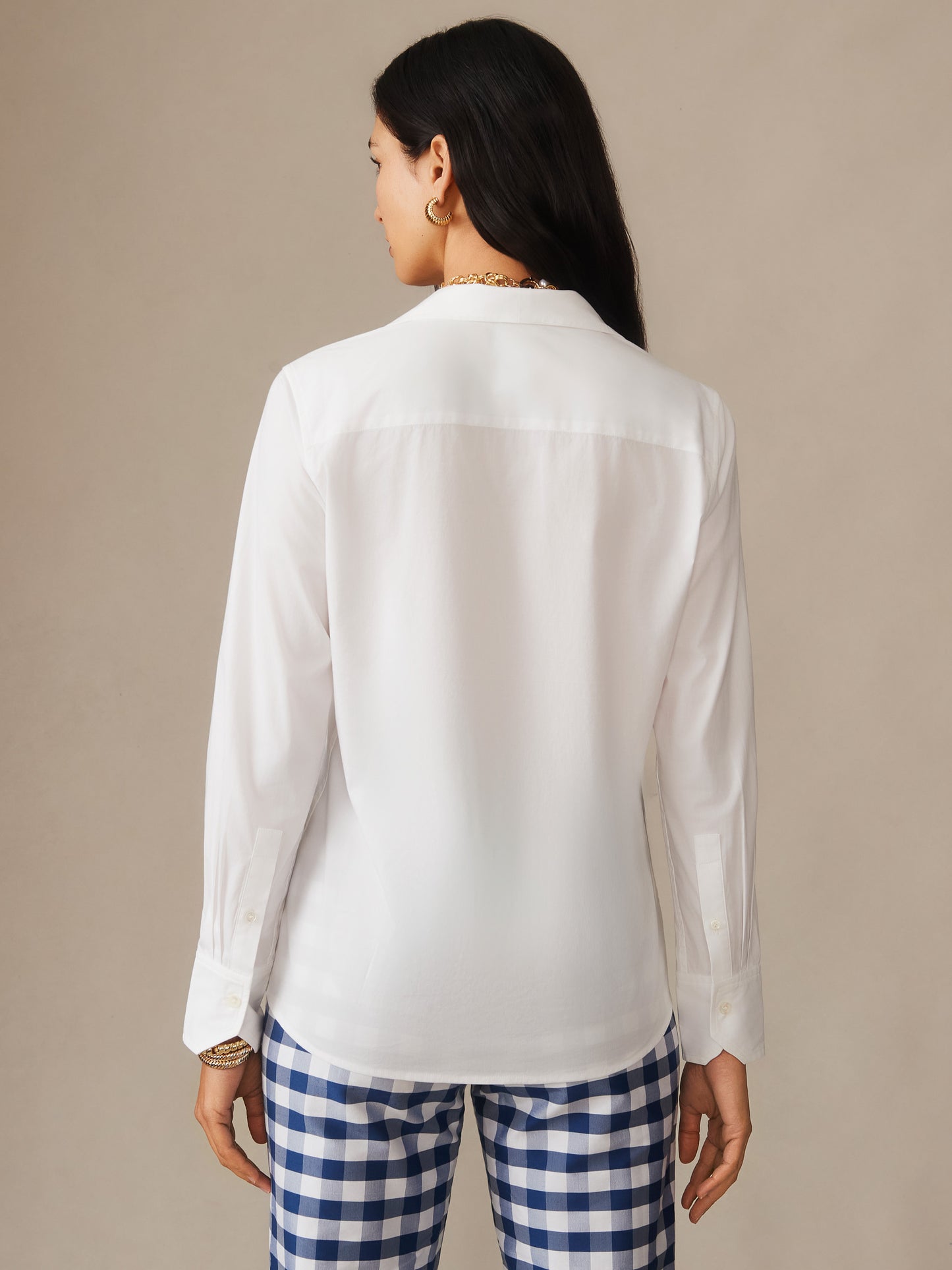Woman wearing a white Victoria Shirt by J.McLaughlin paired with blue and white checkered pants, showcasing effortlessly stylish, enduring designs and innovative fabrics.