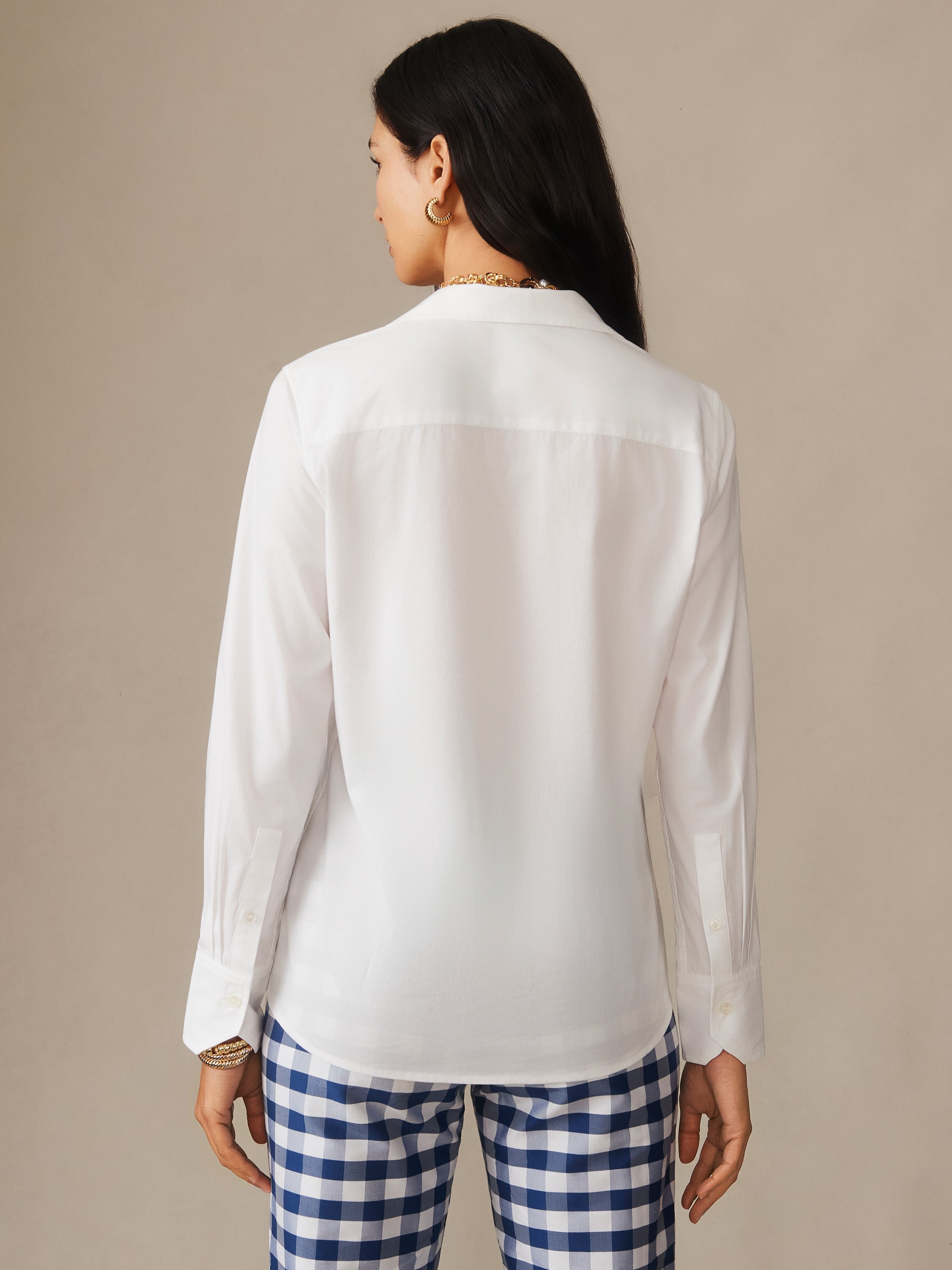 Woman wearing a white Victoria Shirt by J.McLaughlin paired with blue and white checkered pants, showcasing effortlessly stylish, enduring designs and innovative fabrics.