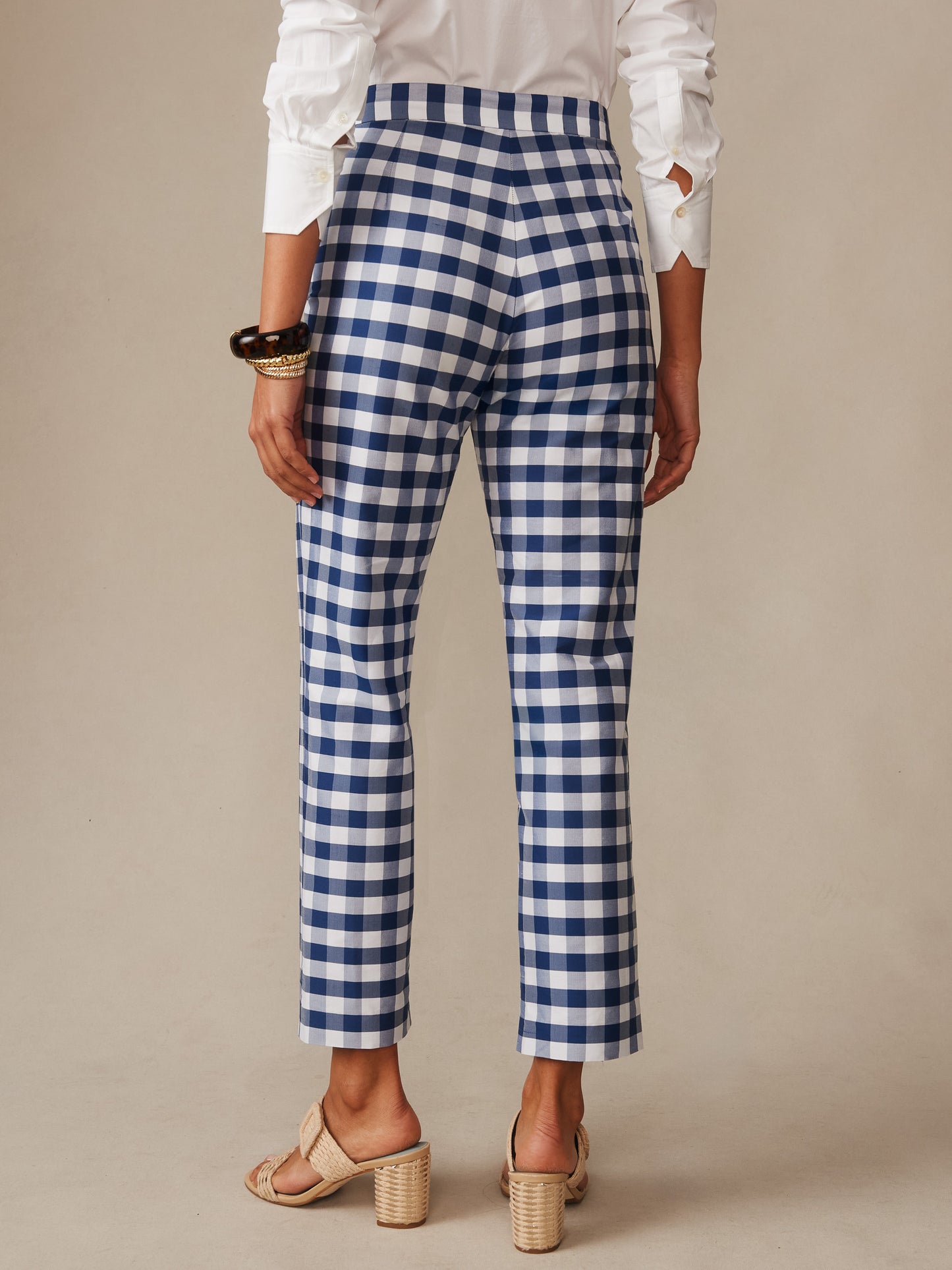 Back view of a person wearing Millbrook Silk Blend Pants in Gingham by J.McLaughlin, featuring classic blue and white check pattern, paired with a white blouse and neutral heeled sandals, exemplifying effortlessly stylish and enduring designs.