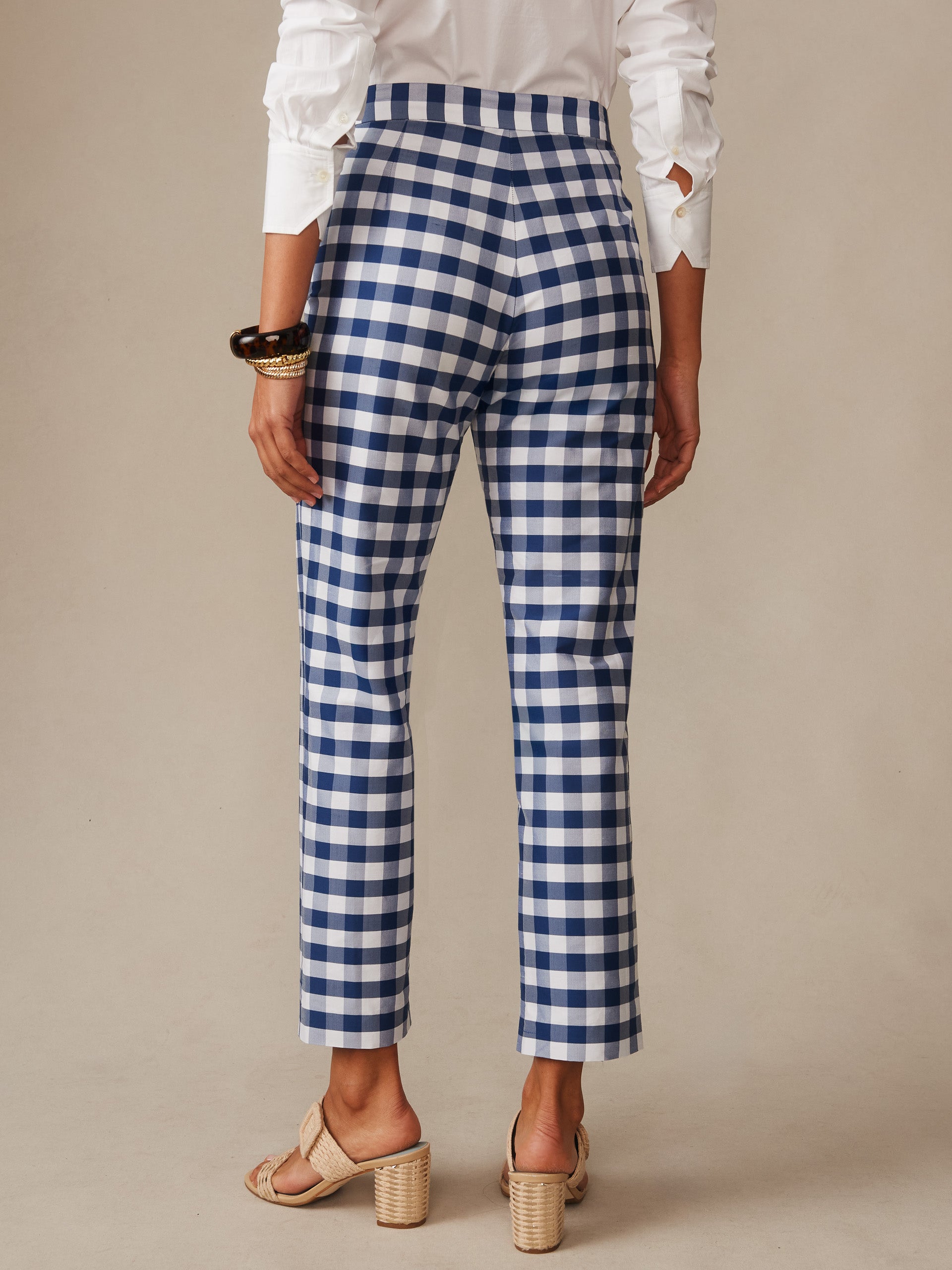 Back view of a person wearing Millbrook Silk Blend Pants in Gingham by J.McLaughlin, featuring classic blue and white check pattern, paired with a white blouse and neutral heeled sandals, exemplifying effortlessly stylish and enduring designs.