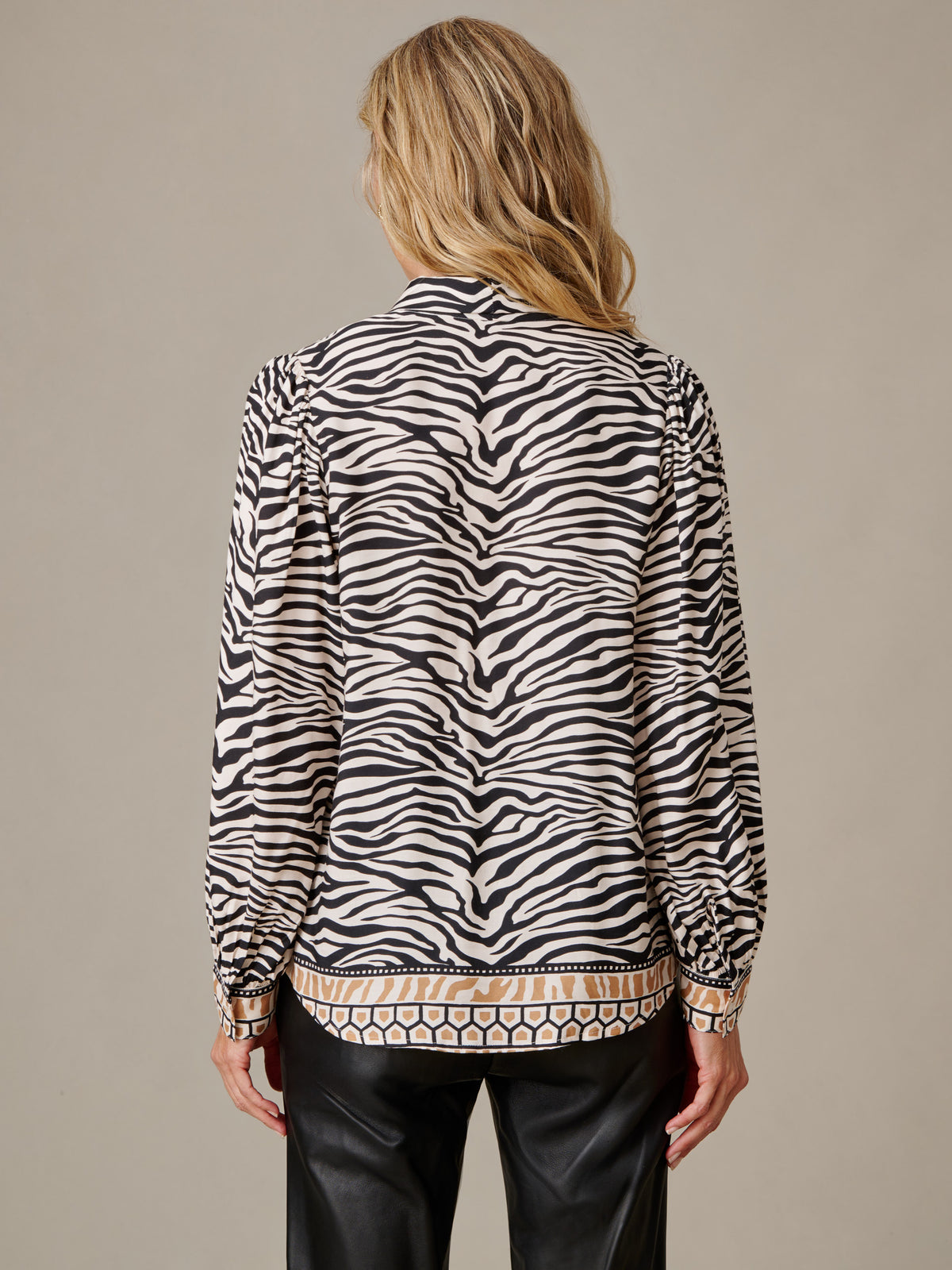 Back view of a model wearing the Vienna Silk Blend Blouse in Mini Zebra Medley Stripe by J.McLaughlin with flowing zebra print and understated volume