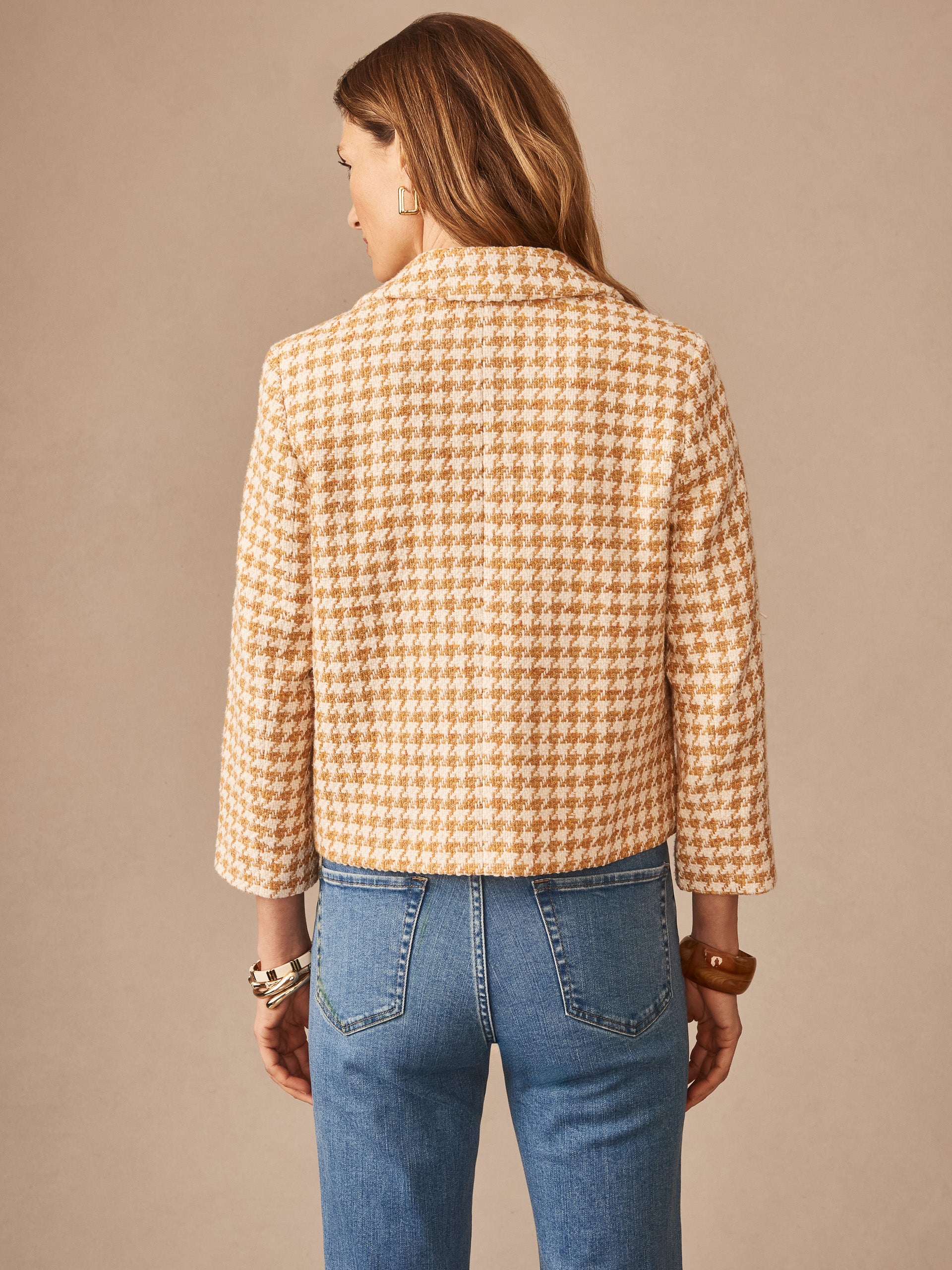 Woman wearing the Violette Tweed Jacket in Houndstooth by J.McLaughlin, styled with jeans and bracelets, showcasing effortlessly stylish, enduring designs in innovative fabrics.