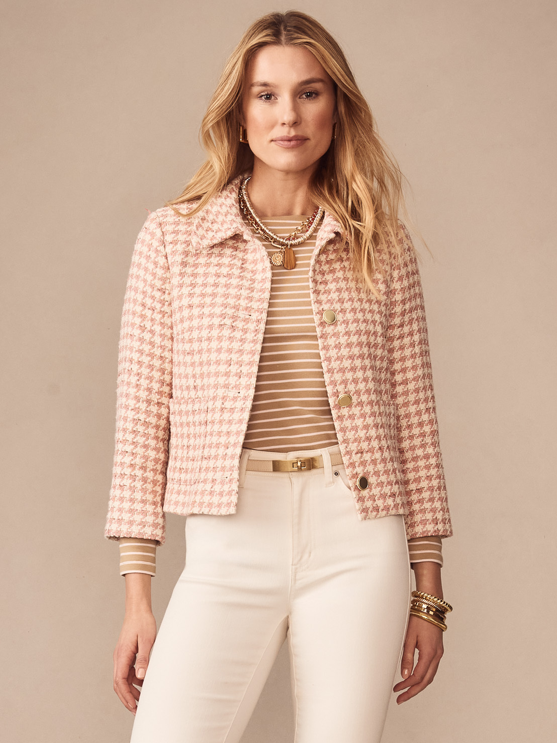 Woman wearing the Violette Tweed Jacket in Houndstooth by J.McLaughlin in soft pink and white, styled with a striped top and white pants, showcasing effortlessly stylish, enduring designs and innovative fabrics.