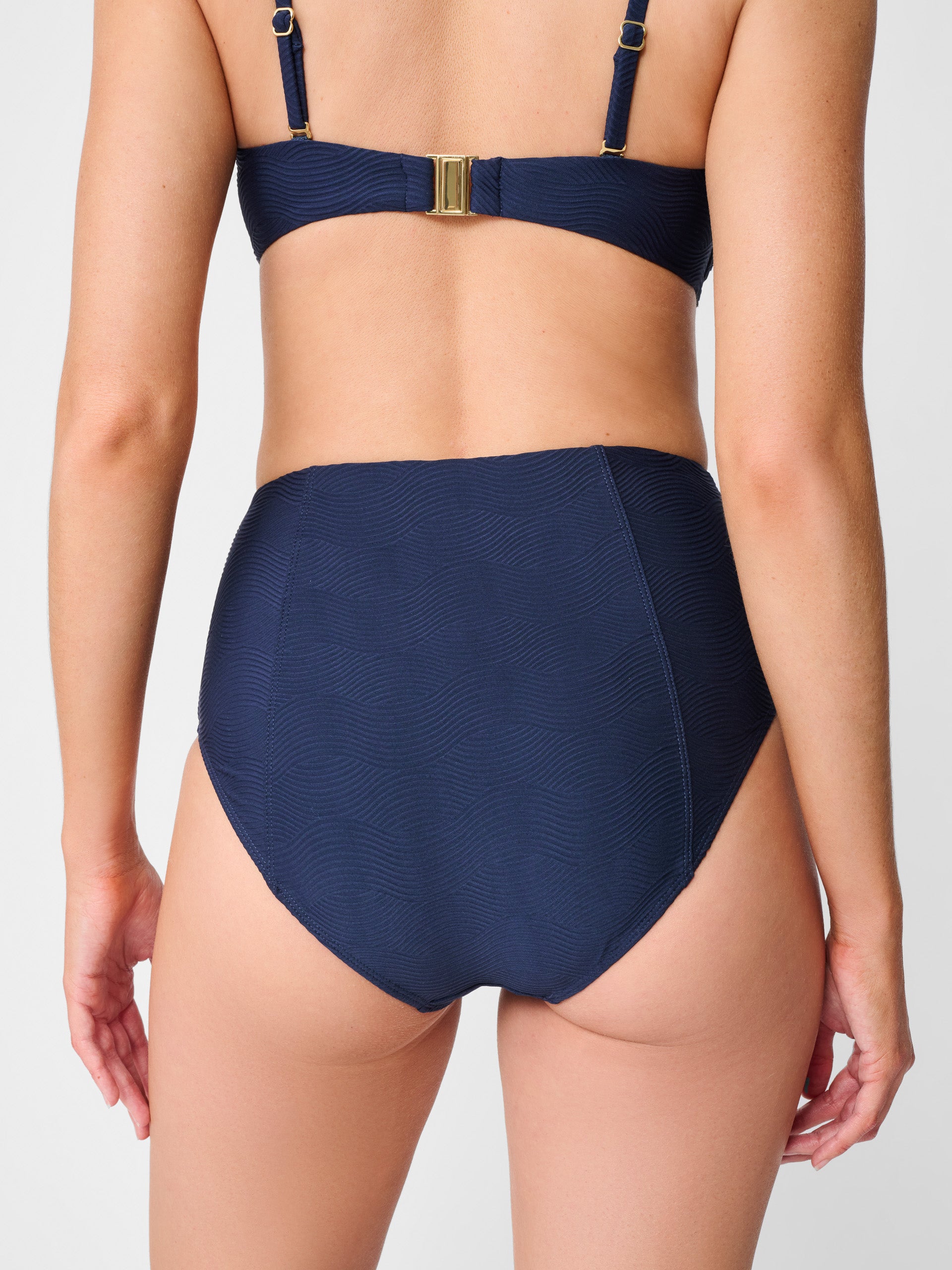 Model wearing J.McLaughlin Wailea bikini bottom in navy made with nylon and lycra.
