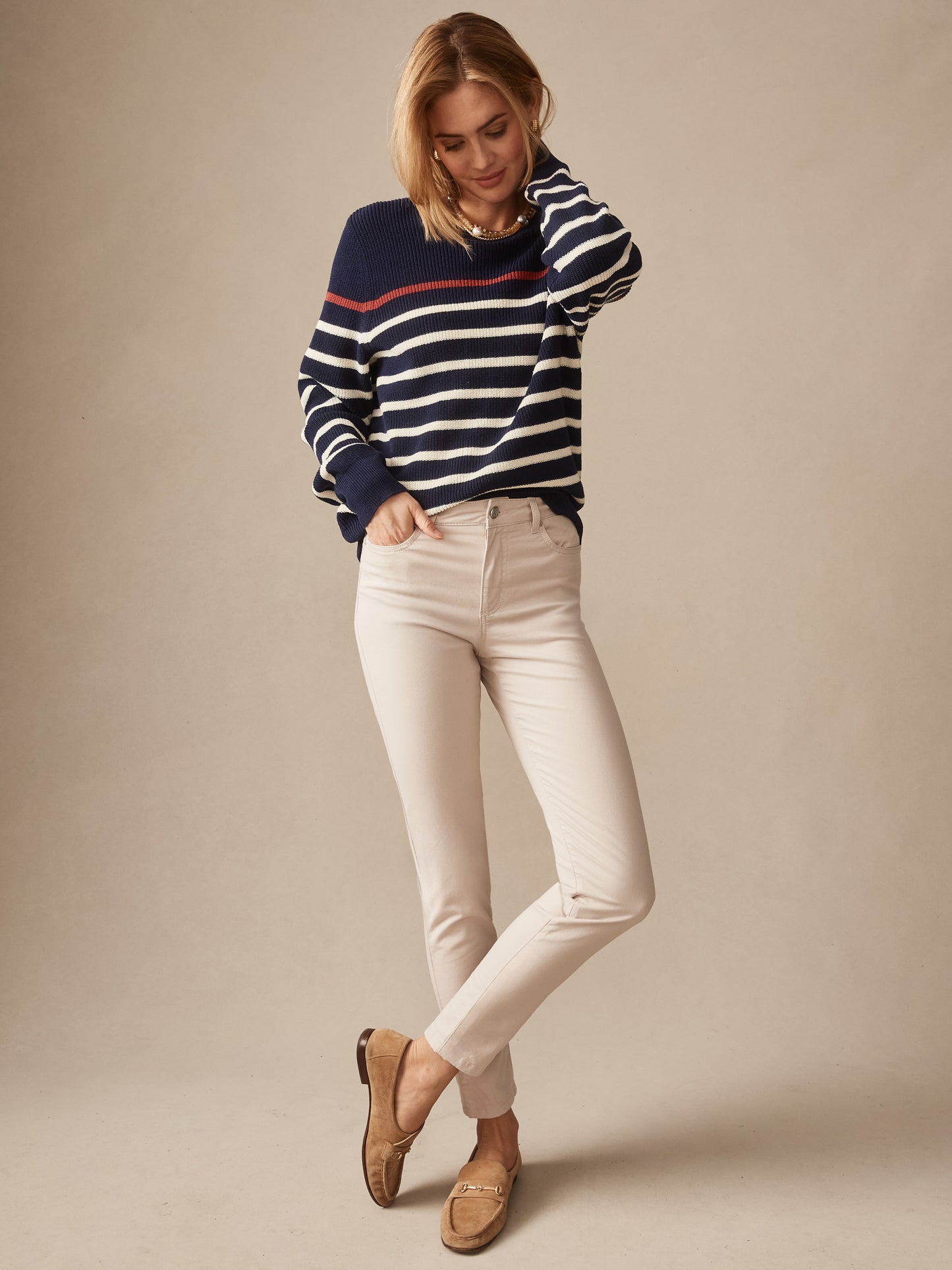 A woman wearing Watson Cotton Cashmere Pants in a soft stone color paired with a classic navy striped sweater and loafers, showcasing J.McLaughlin’s effortlessly stylish, enduring designs and innovative fabrics in a legacy of timeless fashion. A destination for defining style. Life, Well-Lived.