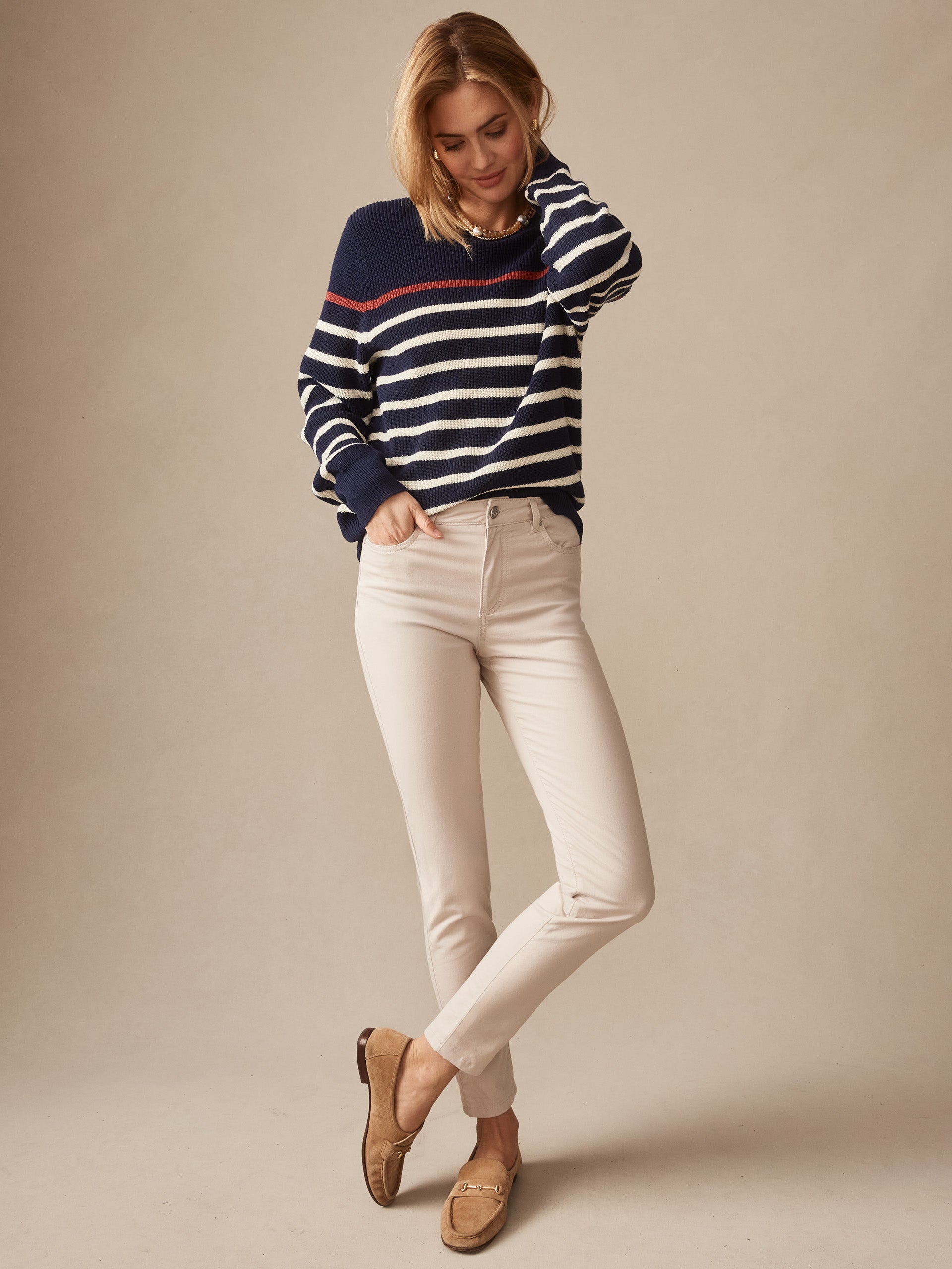 A woman wearing Watson Cotton Cashmere Pants in a soft stone color paired with a classic navy striped sweater and loafers, showcasing J.McLaughlin’s effortlessly stylish, enduring designs and innovative fabrics in a legacy of timeless fashion. A destination for defining style. Life, Well-Lived.