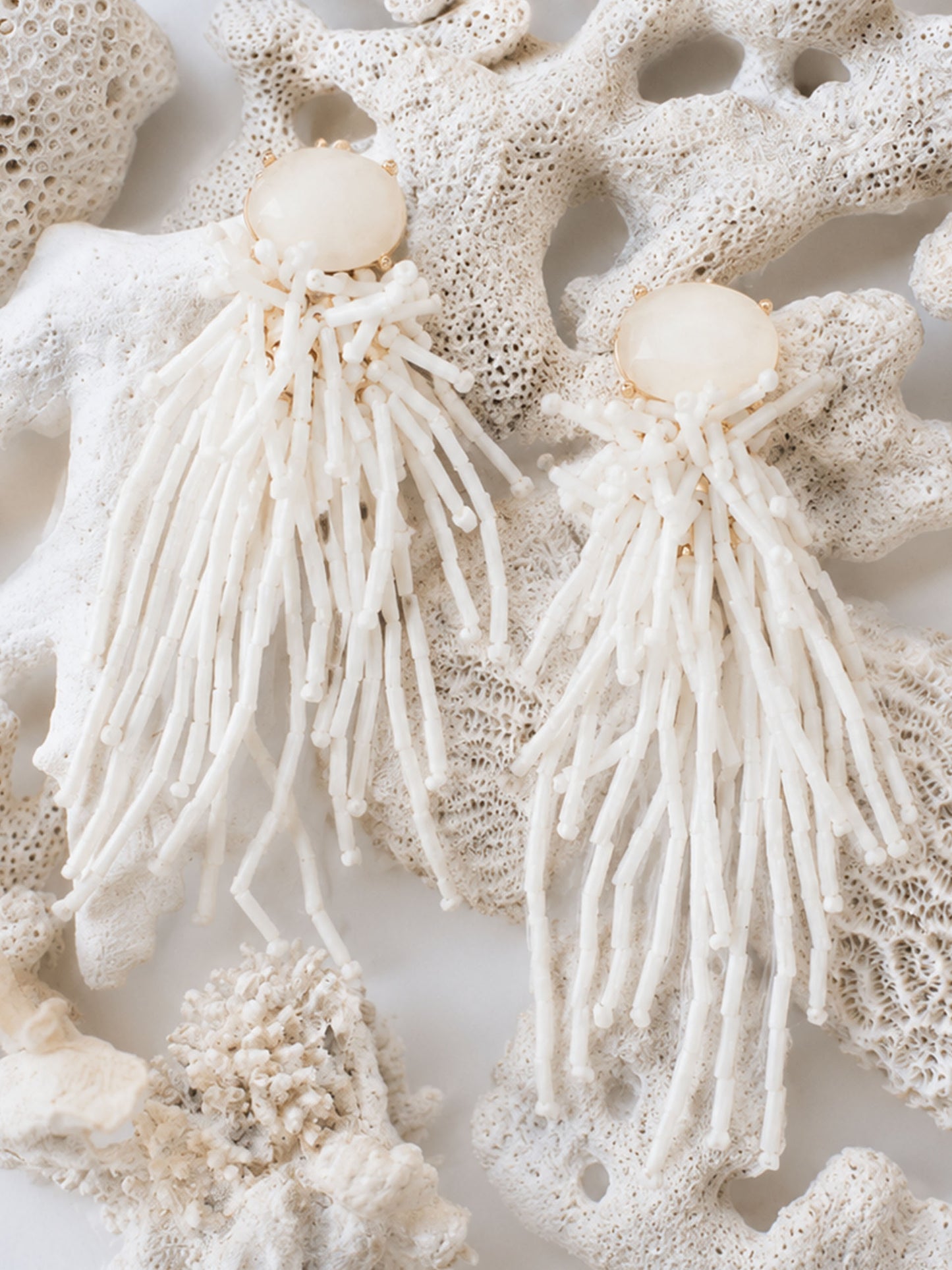 Beaded Tassel Earrings by J.McLaughlin displayed on natural coral, showcasing effortlessly stylish, enduring designs that reflect a legacy of timeless fashion.