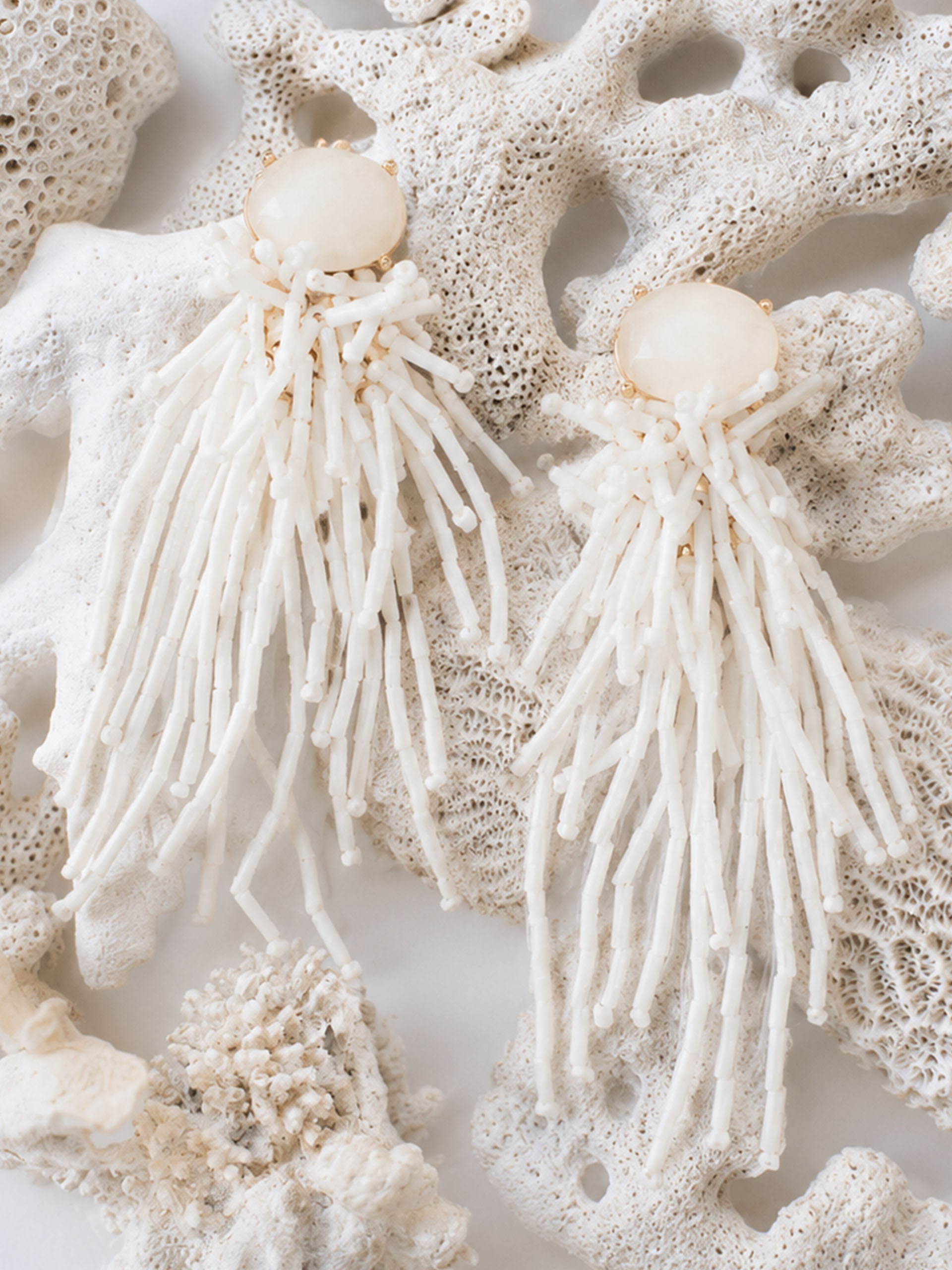 Beaded Tassel Earrings by J.McLaughlin displayed on natural coral, showcasing effortlessly stylish, enduring designs that reflect a legacy of timeless fashion.