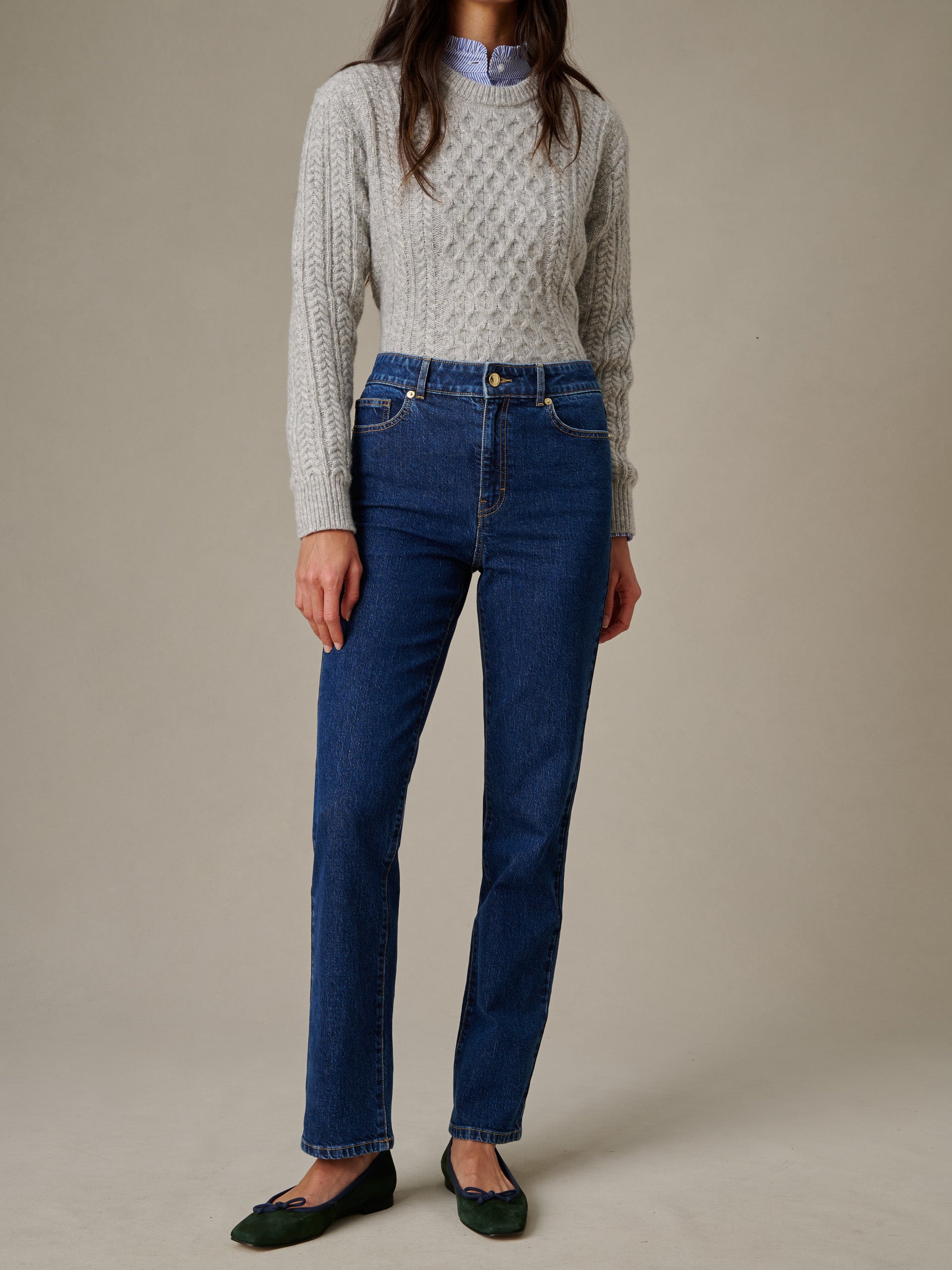 Woman wearing J.McLaughlin Willow Jeans in classic blue denim paired with a gray cable knit sweater and green ballet flats, showcasing timeless style and craftsmanship.