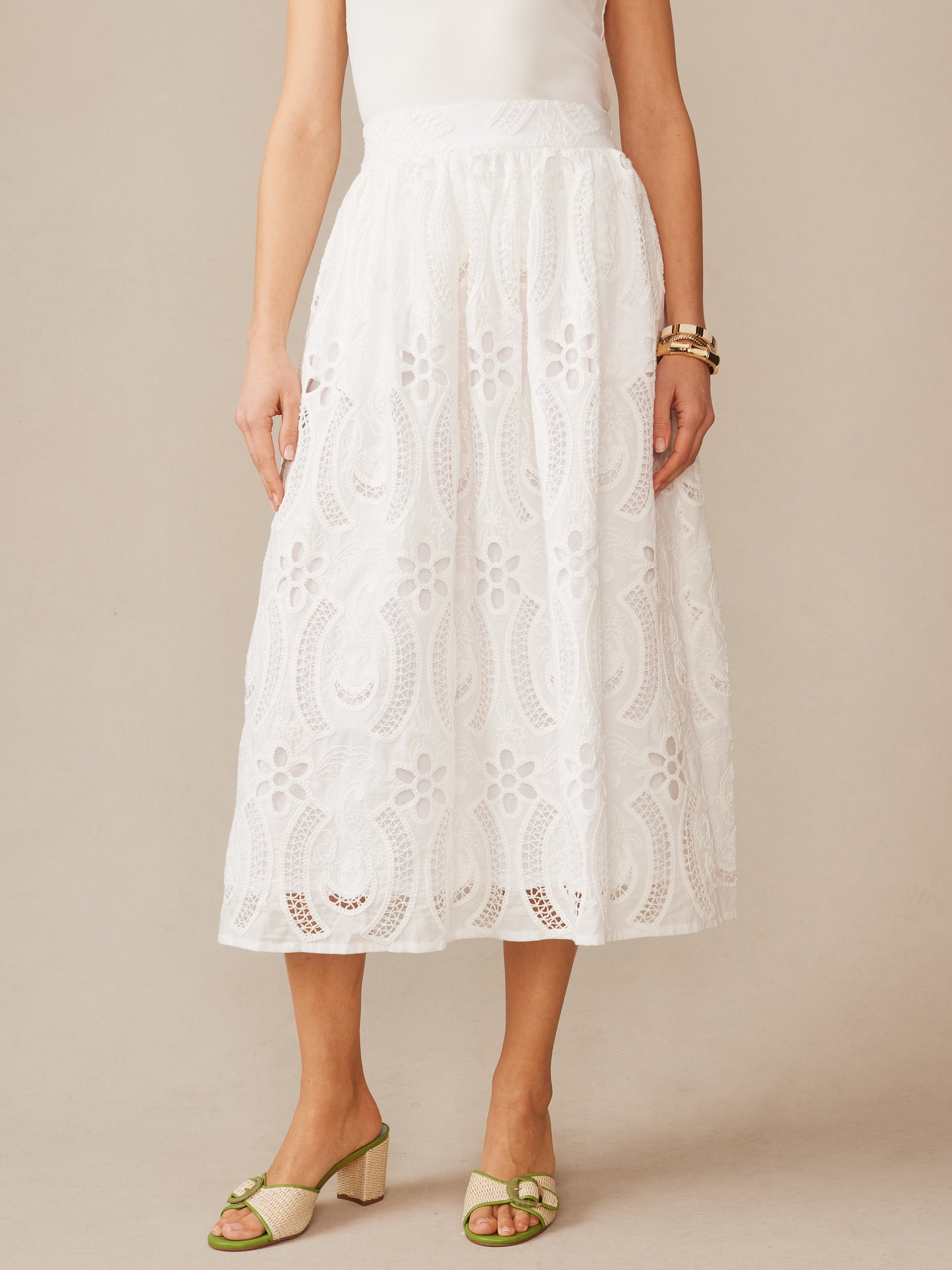 Model wearing the Winnie Skirt in Eyelet by J.McLaughlin, showcasing effortlessly stylish, classic white eyelet fabric skirt with enduring designs for a legacy of timeless fashion. A destination for defining style. Life, Well-Lived.