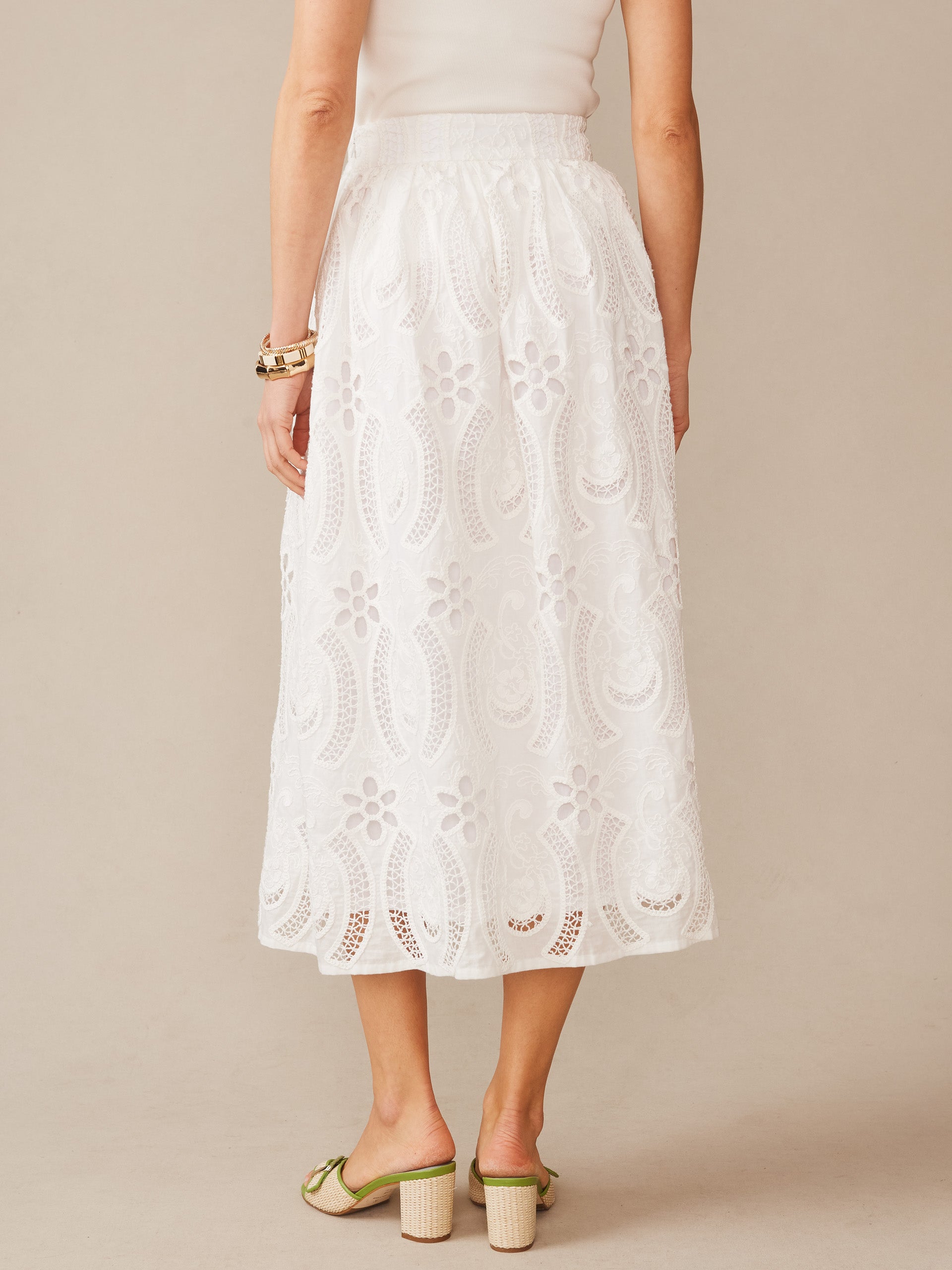 A back view of the Winnie Skirt in Eyelet by J.McLaughlin, showcasing intricate white eyelet fabric with floral and paisley patterns, embodying effortlessly stylish, enduring designs crafted for a destination for defining style. Life, Well-Lived..