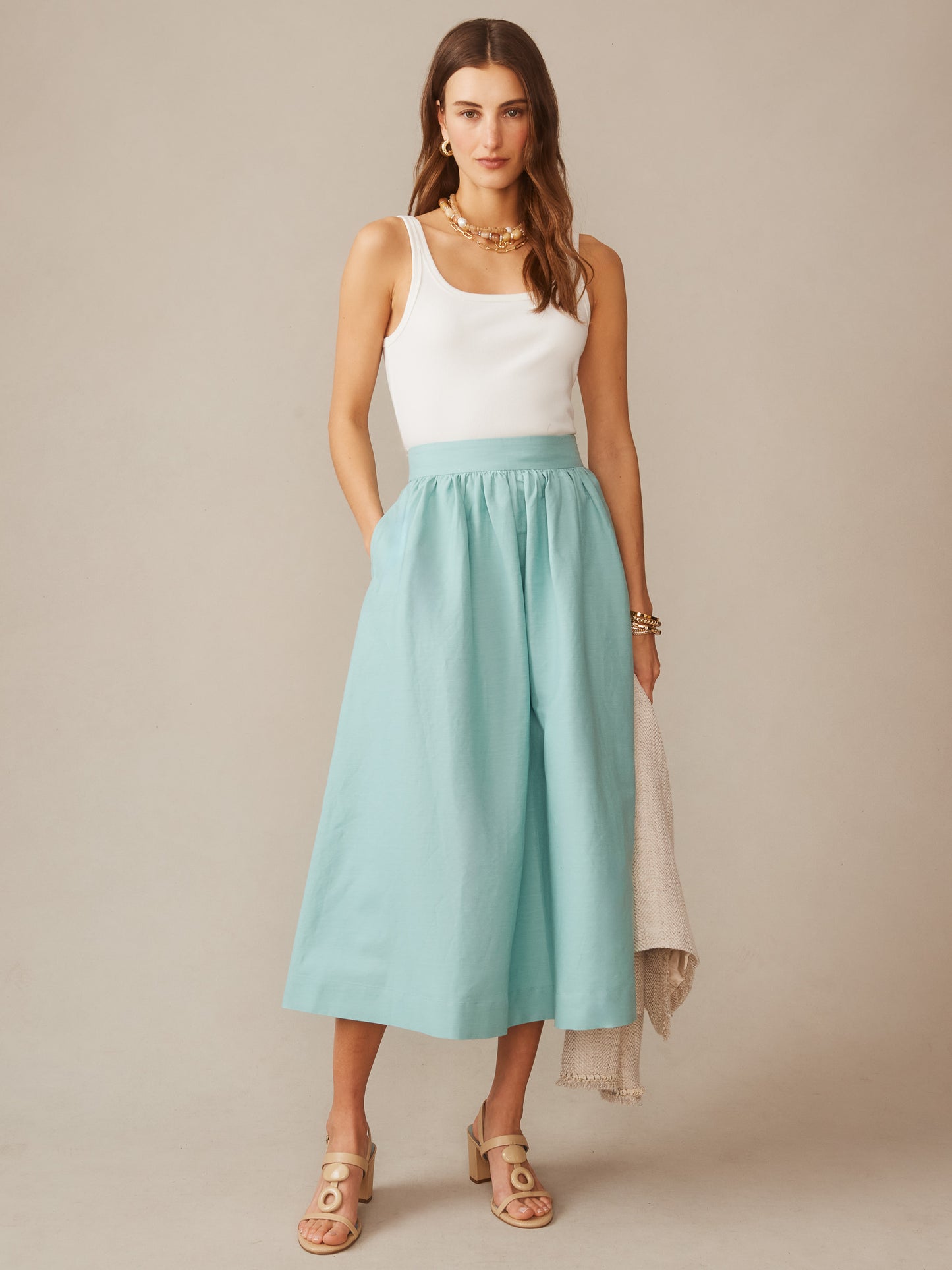 Woman wearing a seafoam Winnie Linen Blend Skirt by J.McLaughlin paired with a white tank top and beige sandals, showcasing effortlessly stylish, enduring designs in timeless fashion.